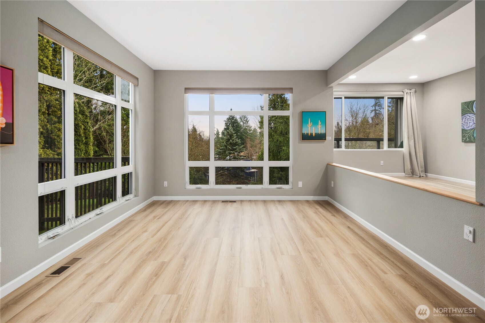 Stylish open kitchen with oversized island, seating, skylight, white cabinetry, stainless appliances, wide plank floors, and seamless entertaining flow design.