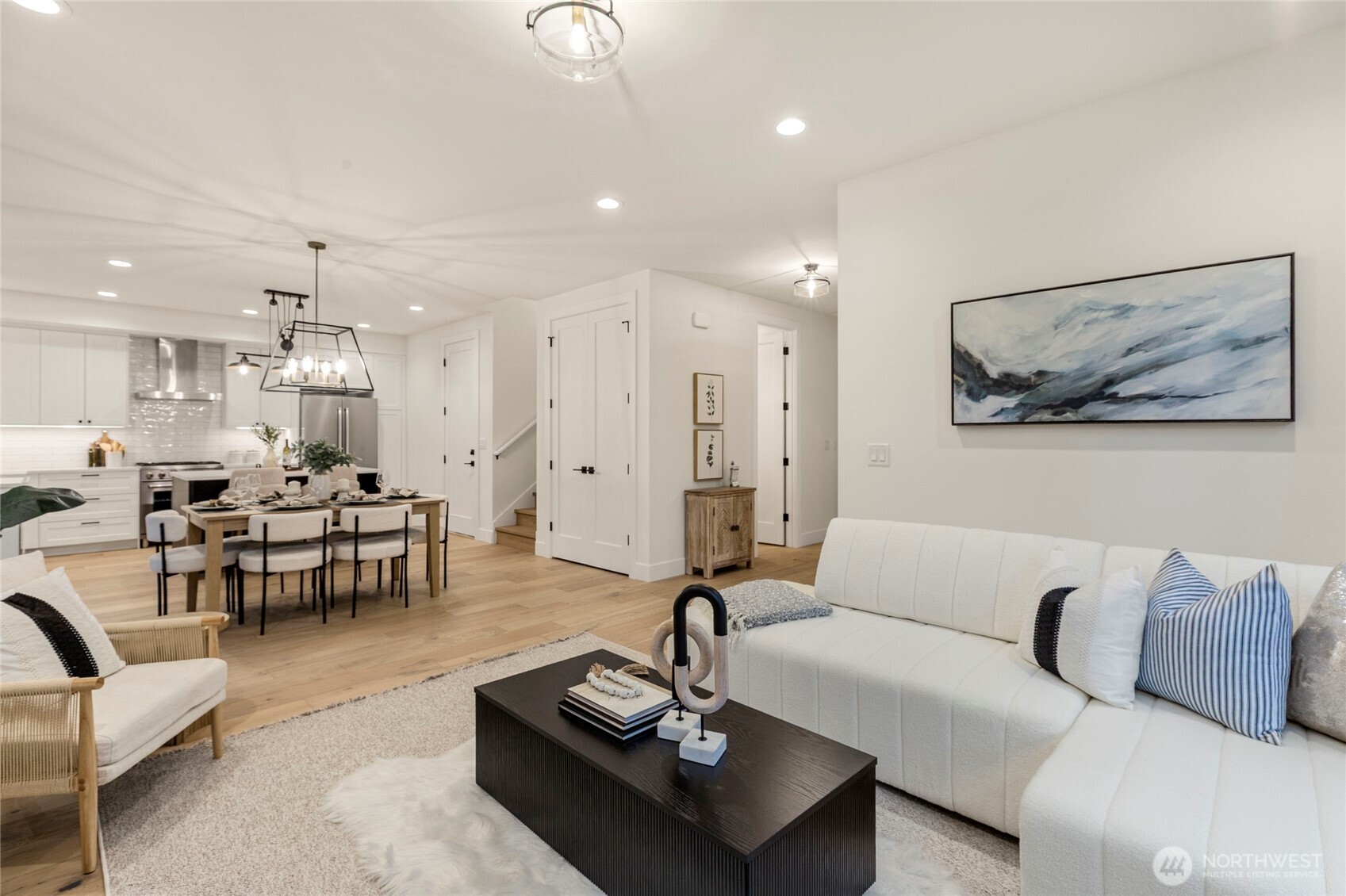 Open-concept living and dining area with recessed lighting, ceiling fixture, and light wood flooring.