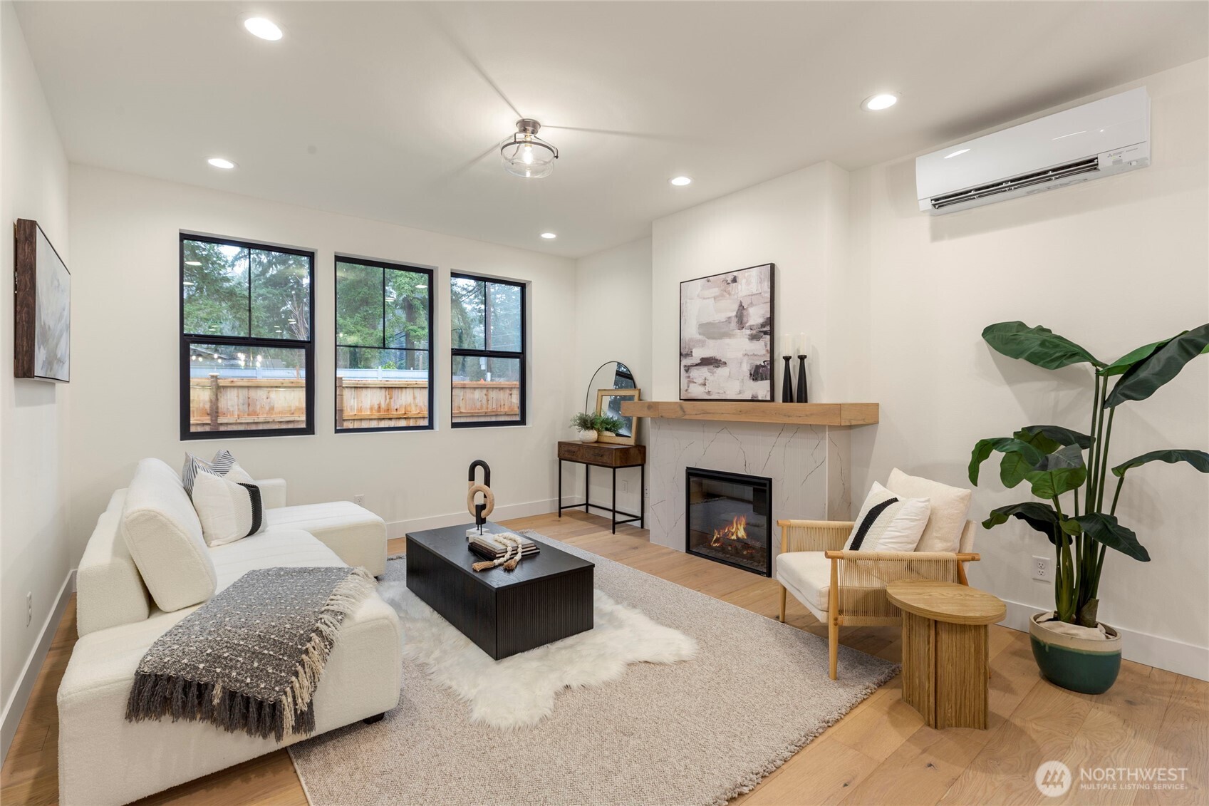 Living room with an electric fireplace, recessed lighting, ceiling fixture, and three black-framed windows.