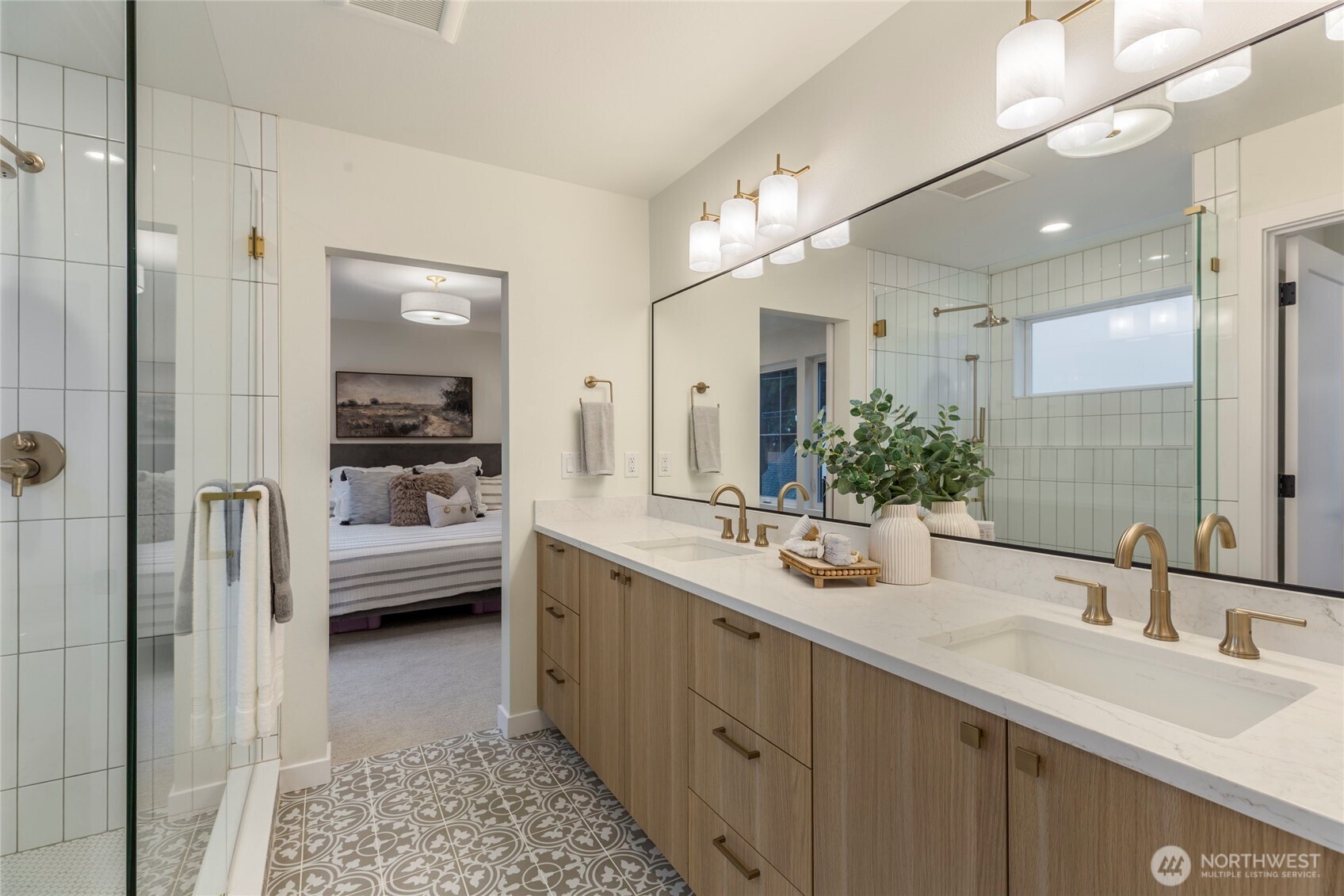 Stylish bathroom with double vanity, gold fixtures, and patterned tile floor.