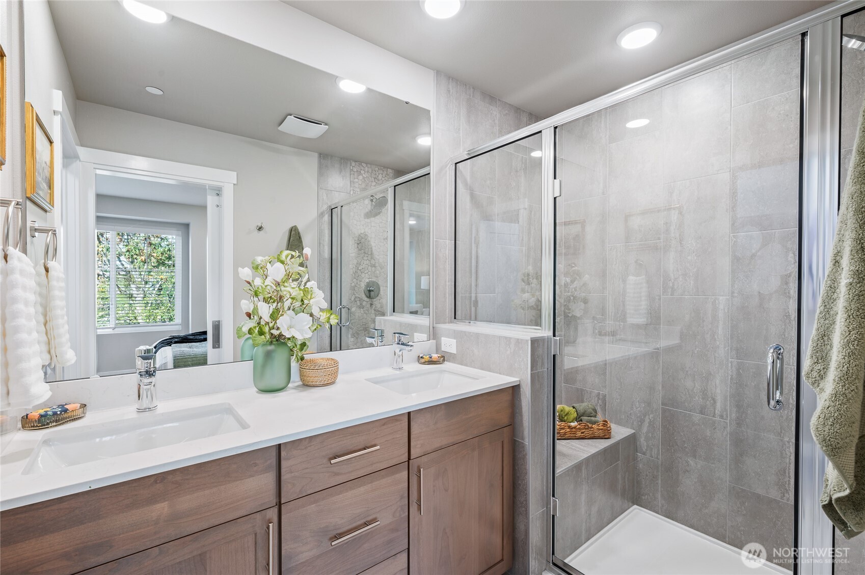 Primary bath. Shower with floor to ceiling title, built in bench and designer tile accents with inset shelf. Photos are of model home in the community.