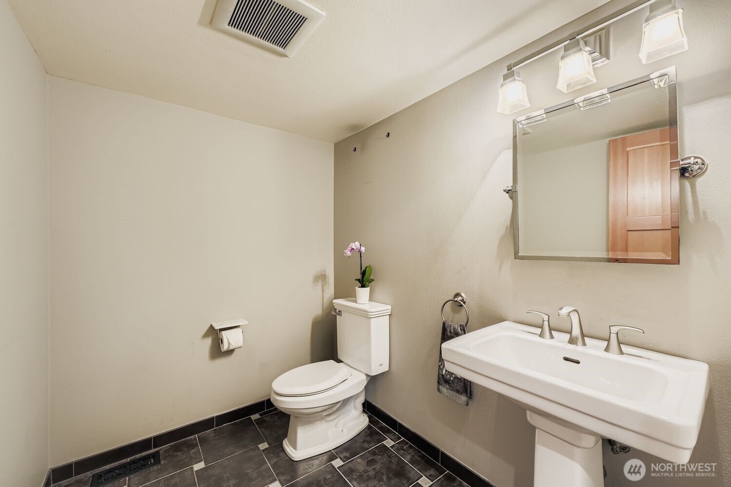 The powder room on the main floor features a pedestal sink, geometric tile floors and attractive lighting.
