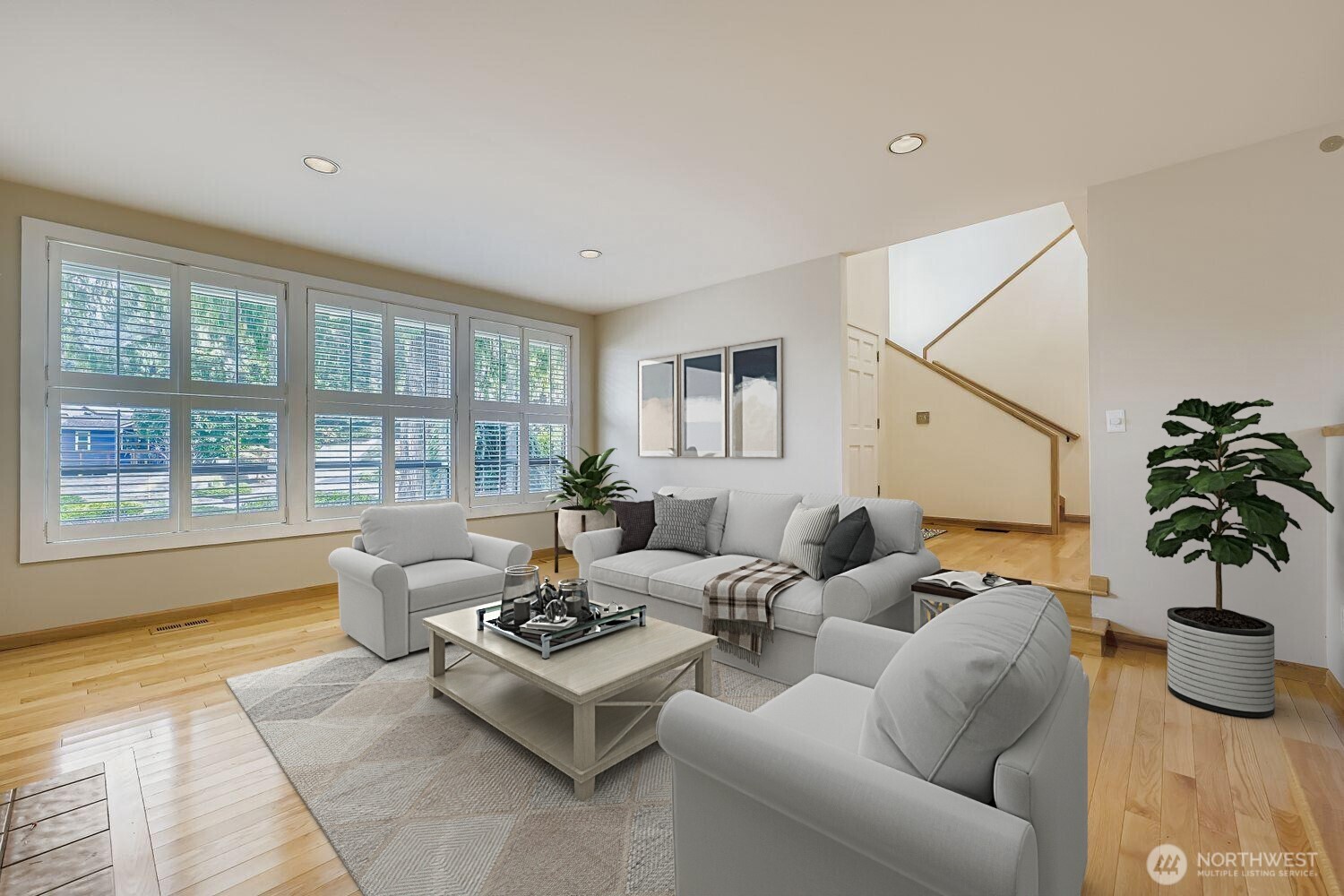 The spacious living room features gleaming hardwood floors, a wall of windows to the front and beautiful plantation shutters.