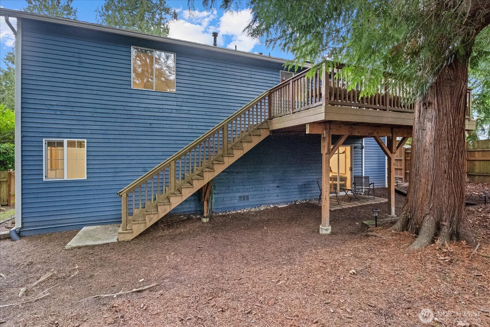 Winter view of the fenced backyard featuring a grassy area for relaxation, a side garden, and a playhouse.