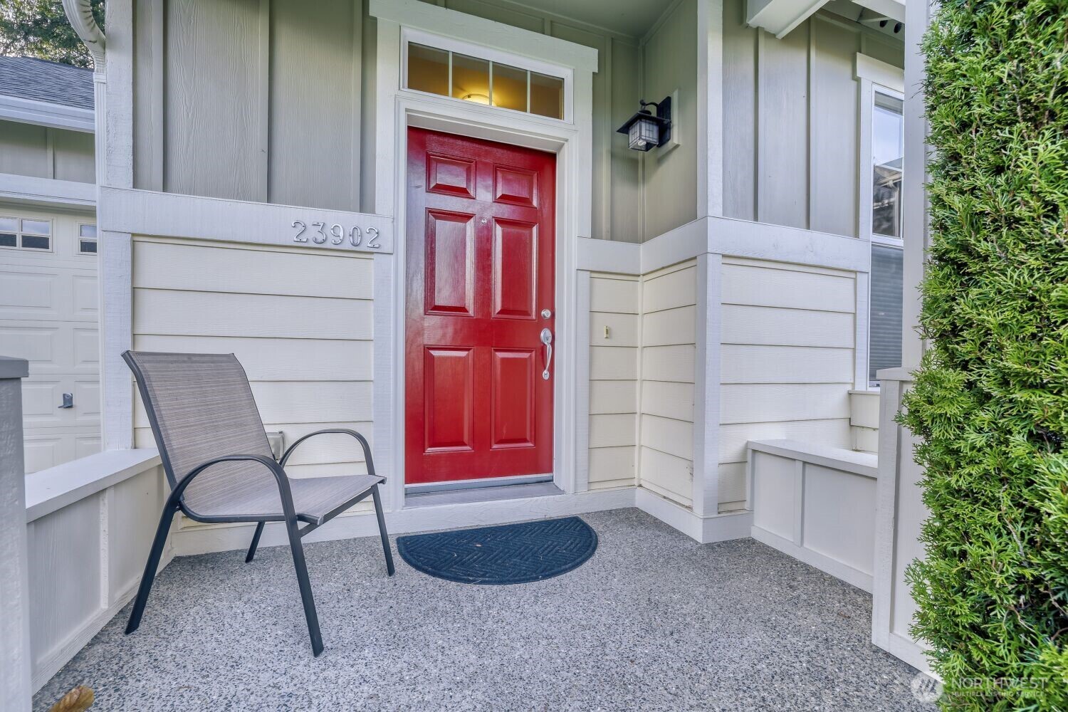 Welcoming front porch surrounded by beautiful mature trees and greenery.