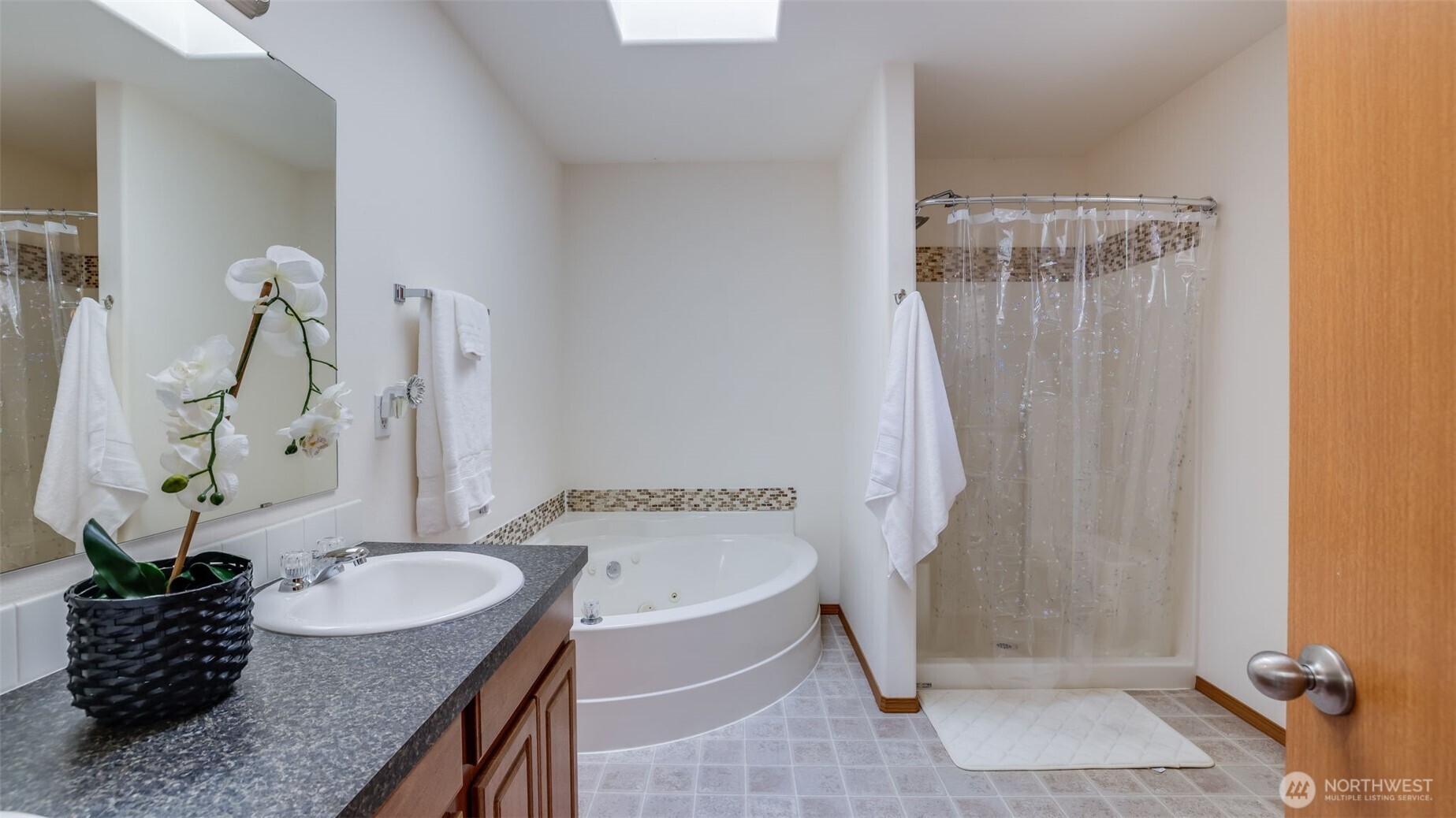 Unwind in your private en suite featuring a soaking tub, separate walk-in shower, and a serene layout
