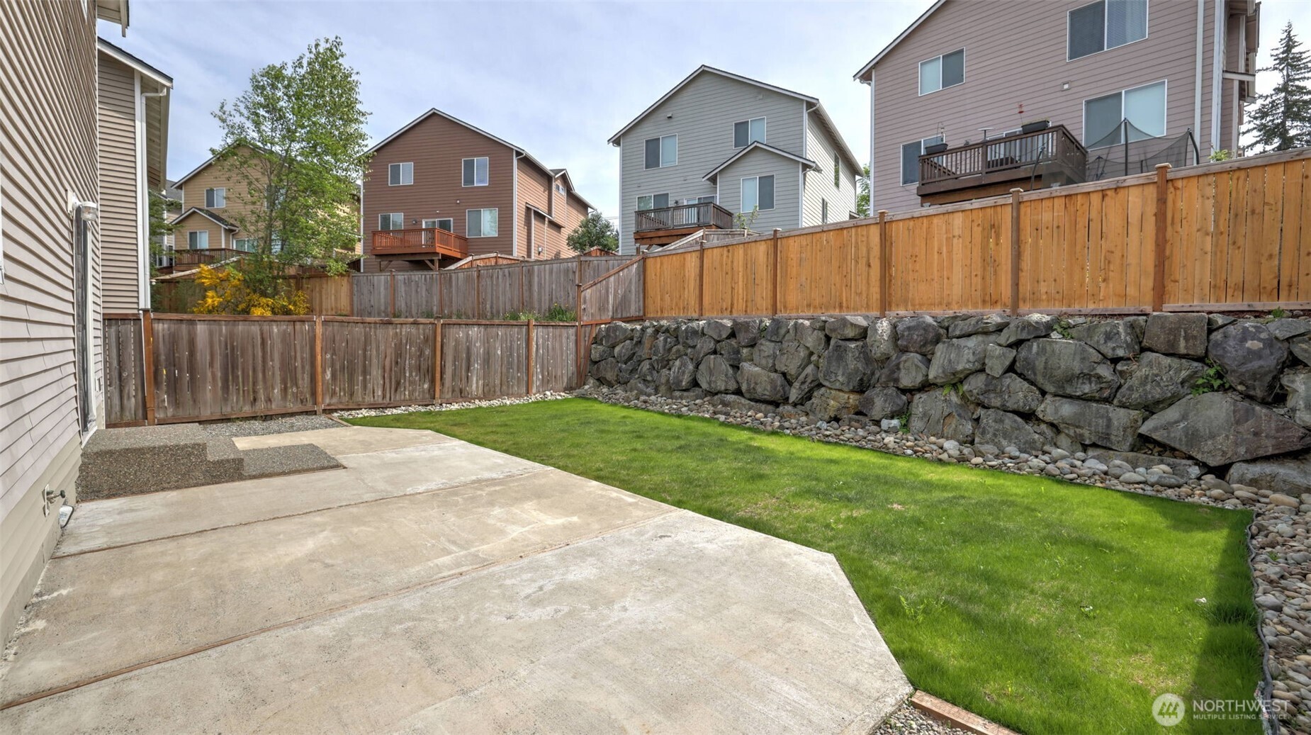 Relax or entertain in this peaceful backyard oasis with brand-new grass, a generous patio space, and a charming rock wall—all enclosed for your privacy and comfort
