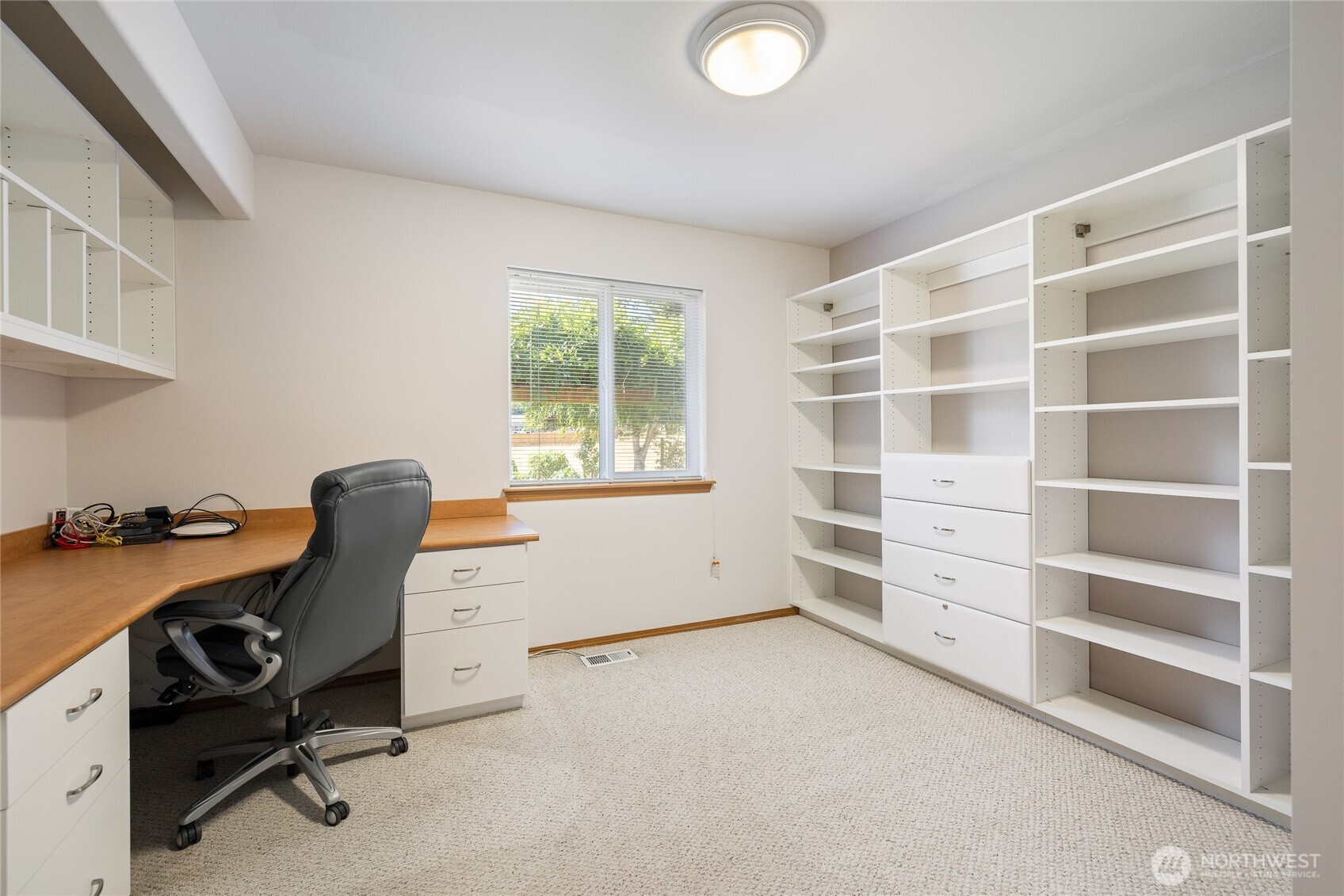 One bedroom currently being used as an office featuring crisp white built-ins for organized storage.
