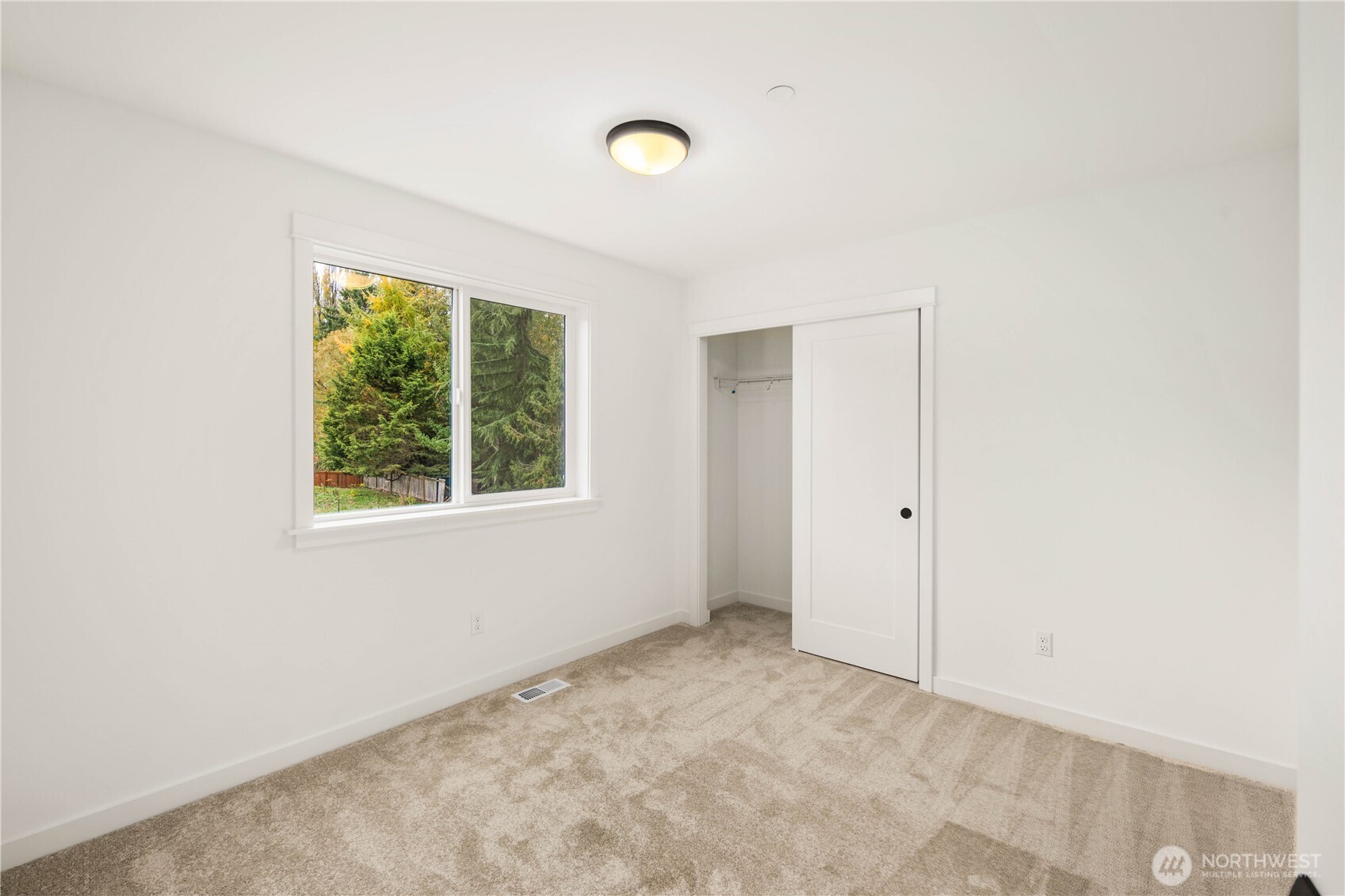 This comfortable secondary bedroom features a wide window overlooking mature evergreens for added privacy and natural serenity. Its neutral finishes and generous layout make it an easy canvas for a variety of uses, from sleeping space to study or flex room.    These photos are from lot 3 at Gooden Hollow, the actual home for sale. However, other homes may vary, so all photos, renderings, site maps, and floorplans are for visualization purposes only. Plans, colors, building orientation, finishes, home outlook, and other details can and WILL vary.