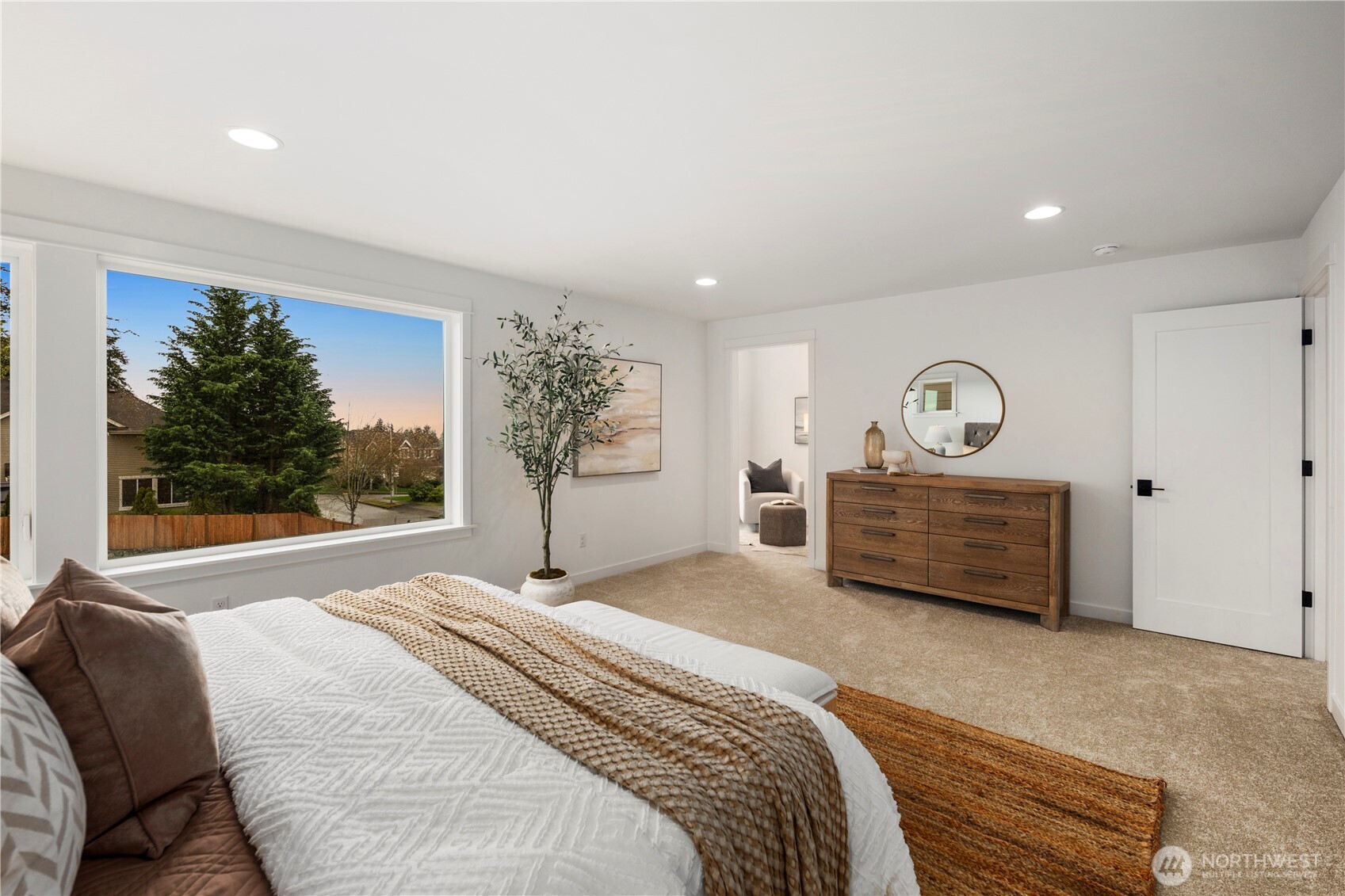 Primary Bedroom Alternate View: Large picture window frames territorial scenery, enhancing the room’s open feel. Direct access to the sitting room and ensuite bath makes this a true owner’s sanctuary.    Photos are from the model home at Foxmoore and for visualization purposes only. Plans, colors, building orientation, finishes, home outlook, and other details can and WILL vary.