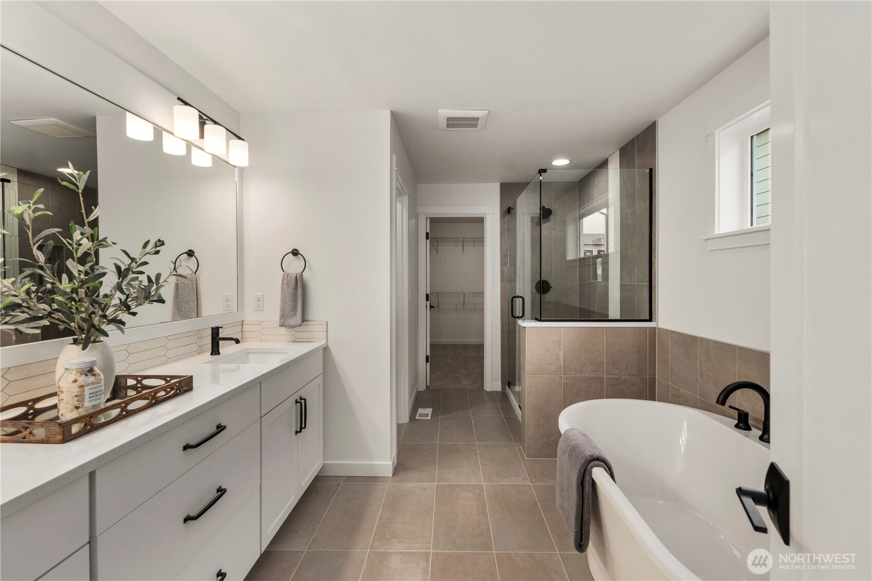 Primary Bath: Luxurious spa-inspired bath features dual vanities, quartz counters, soaking tub, and a glass-enclosed shower. Elegant finishes pair with abundant natural light, creating a rejuvenating retreat.    Photos are from the model home at Foxmoore and for visualization purposes only. Plans, colors, building orientation, finishes, home outlook, and other details can and WILL vary.