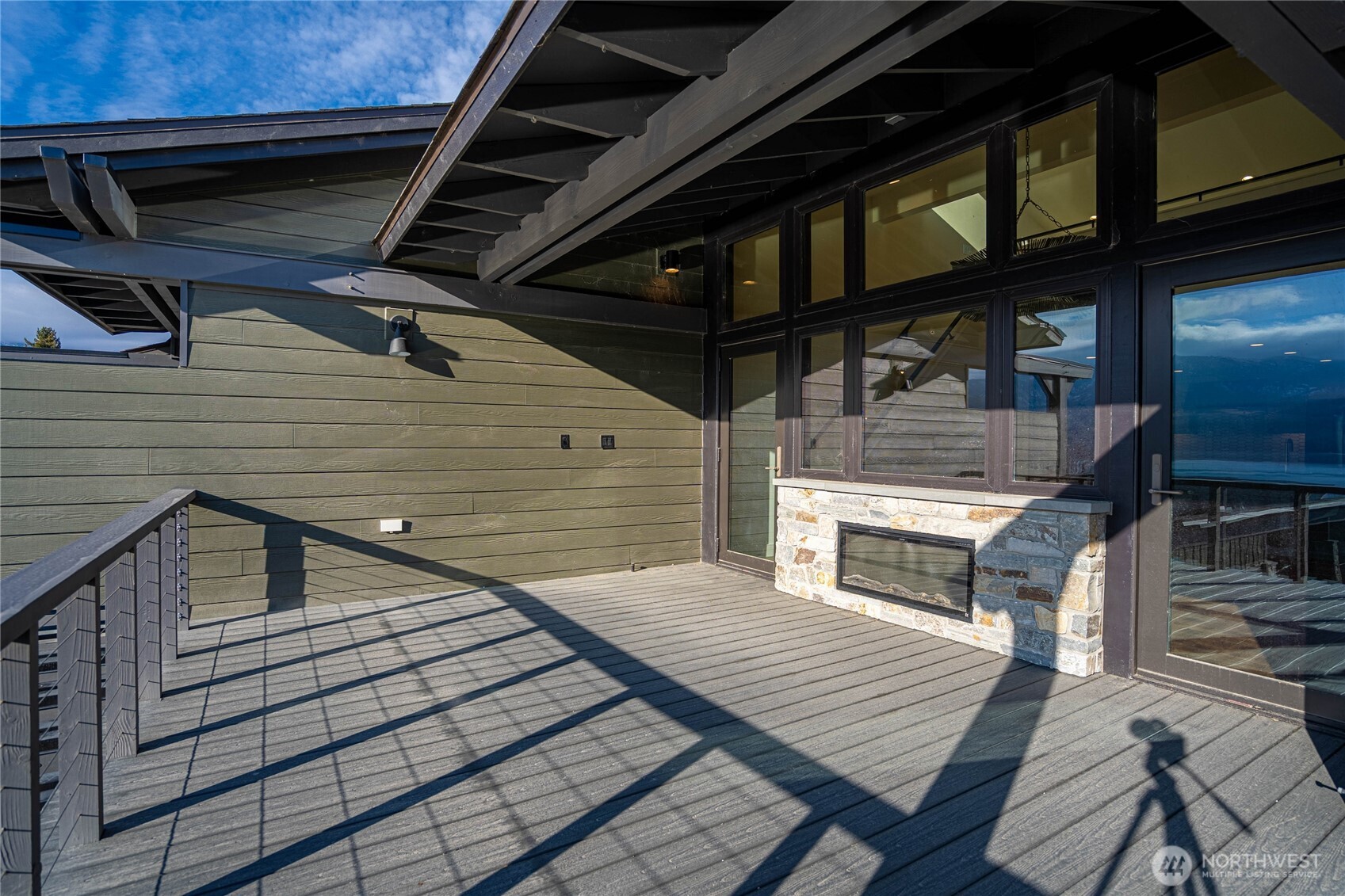 Indoor outdoor living with the fireplace and twin doors opening to the deck with two-side fireplace for indoor and outdoor enjoyment.