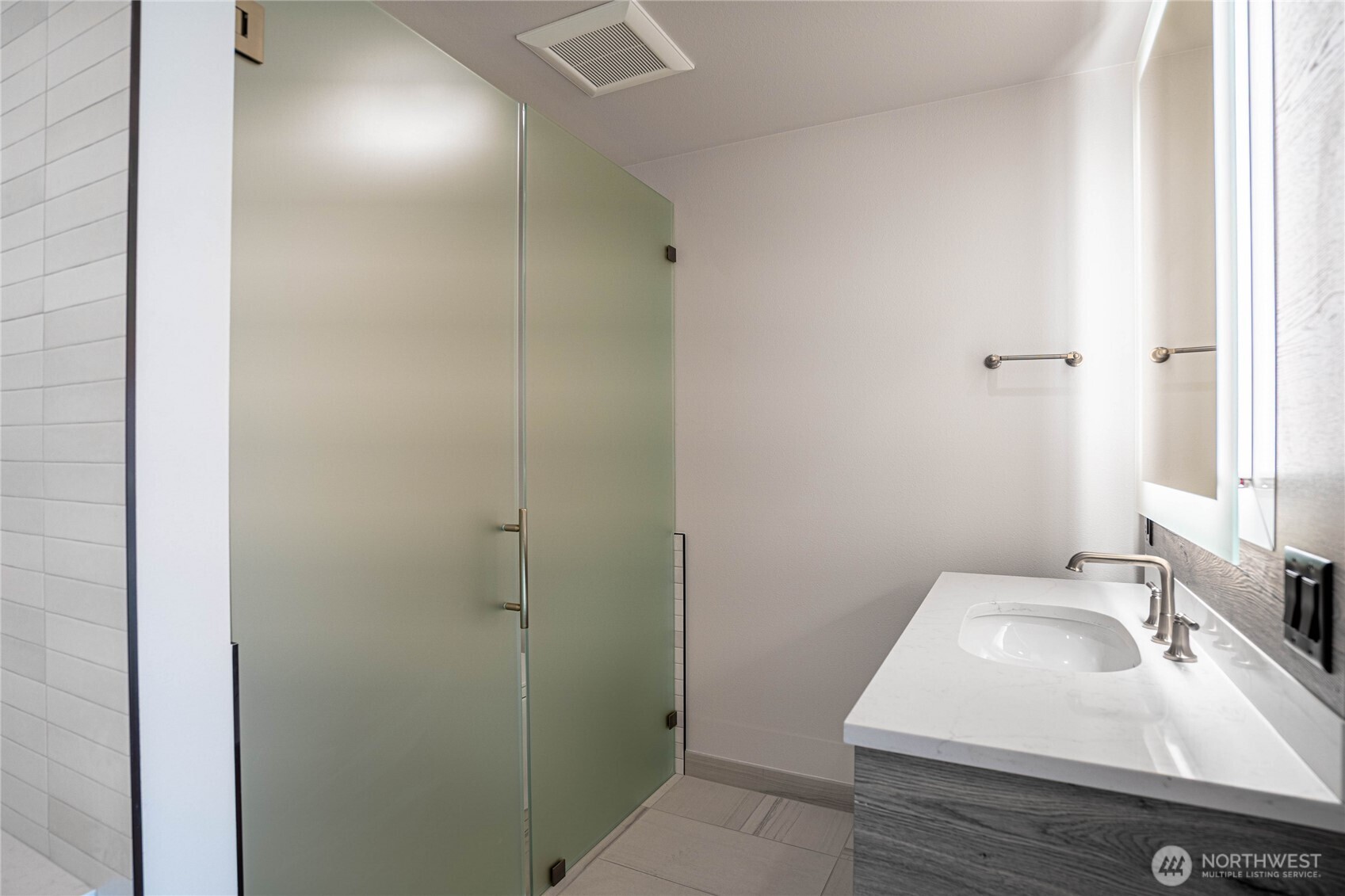 Twin bathroom sinks in the en suite primary bathroom with halo-illuminated mirrors and separate toilet area with privacy glass doors.
