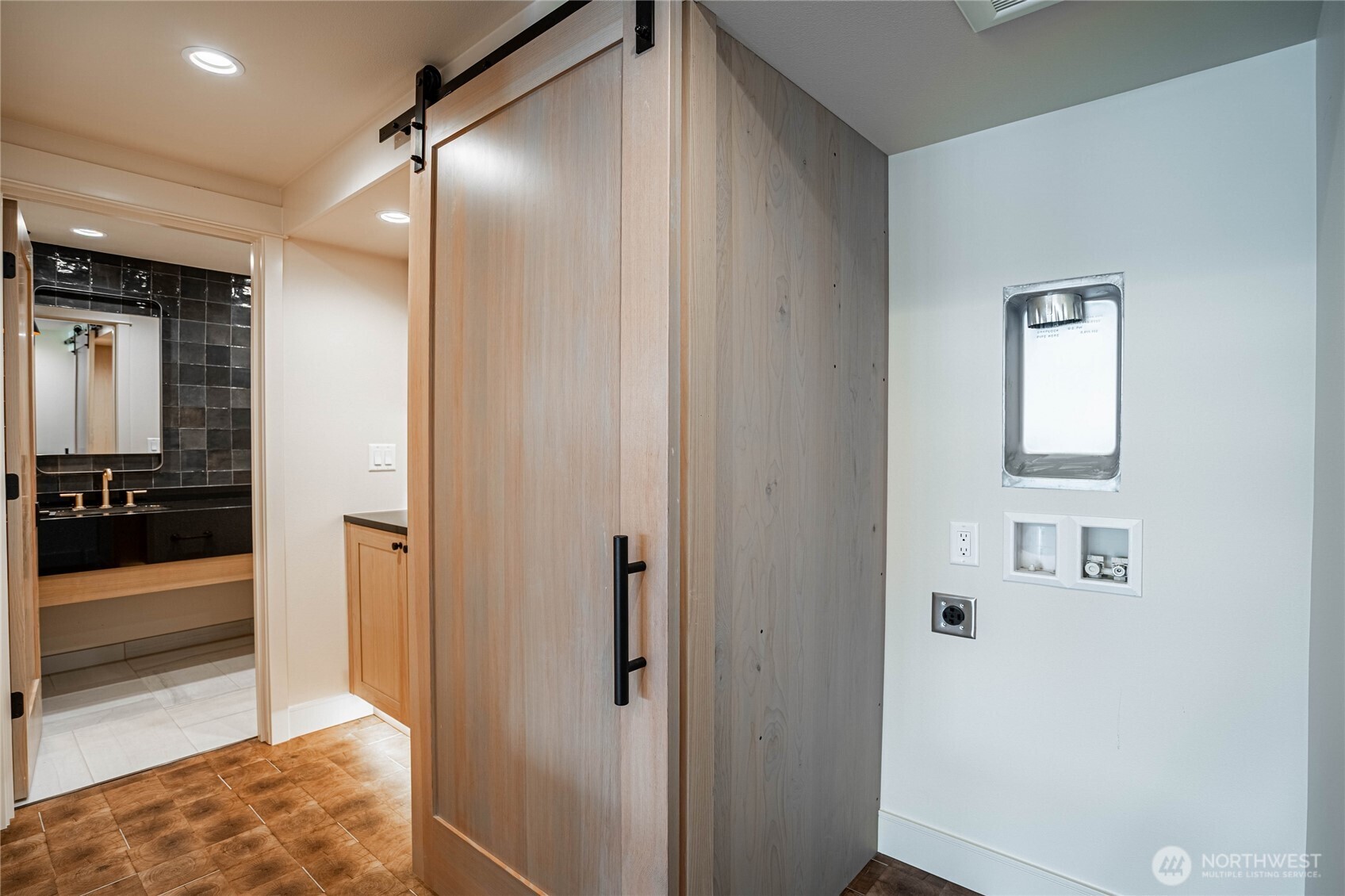 Laundry area for stacking washer/dryer are concealed with a barn door in the hallway to the guest bathroom.