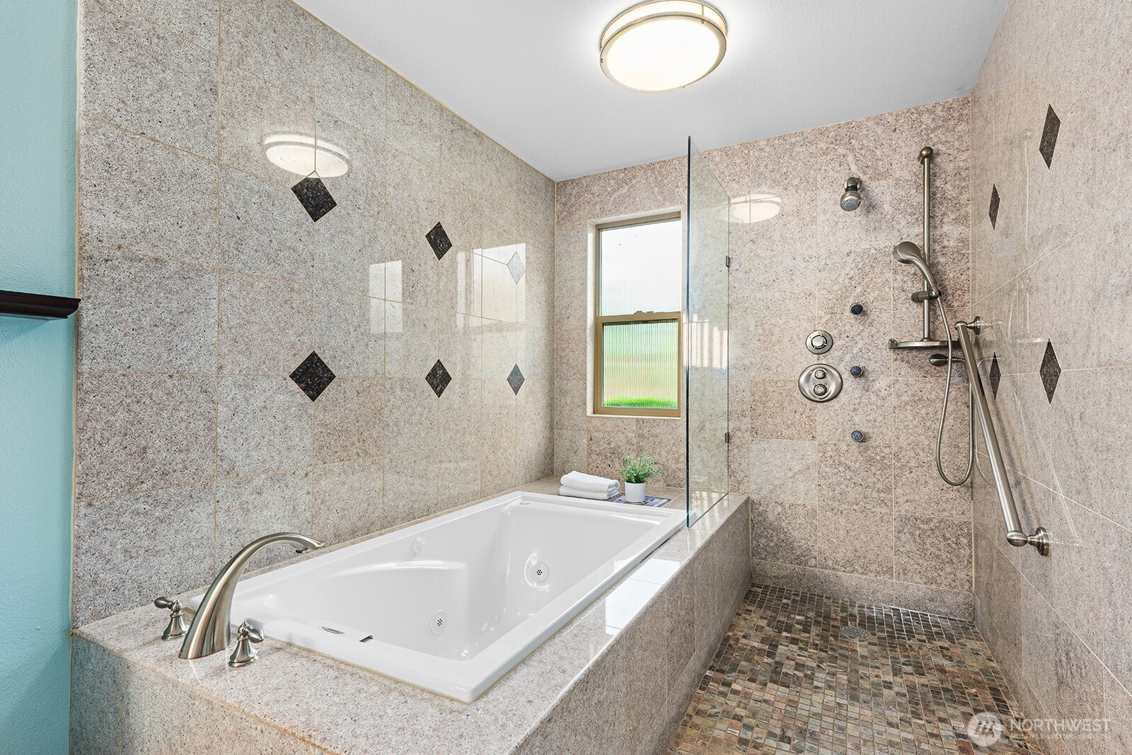 The walk-in shower features a natural stone base and multiple shower heads.