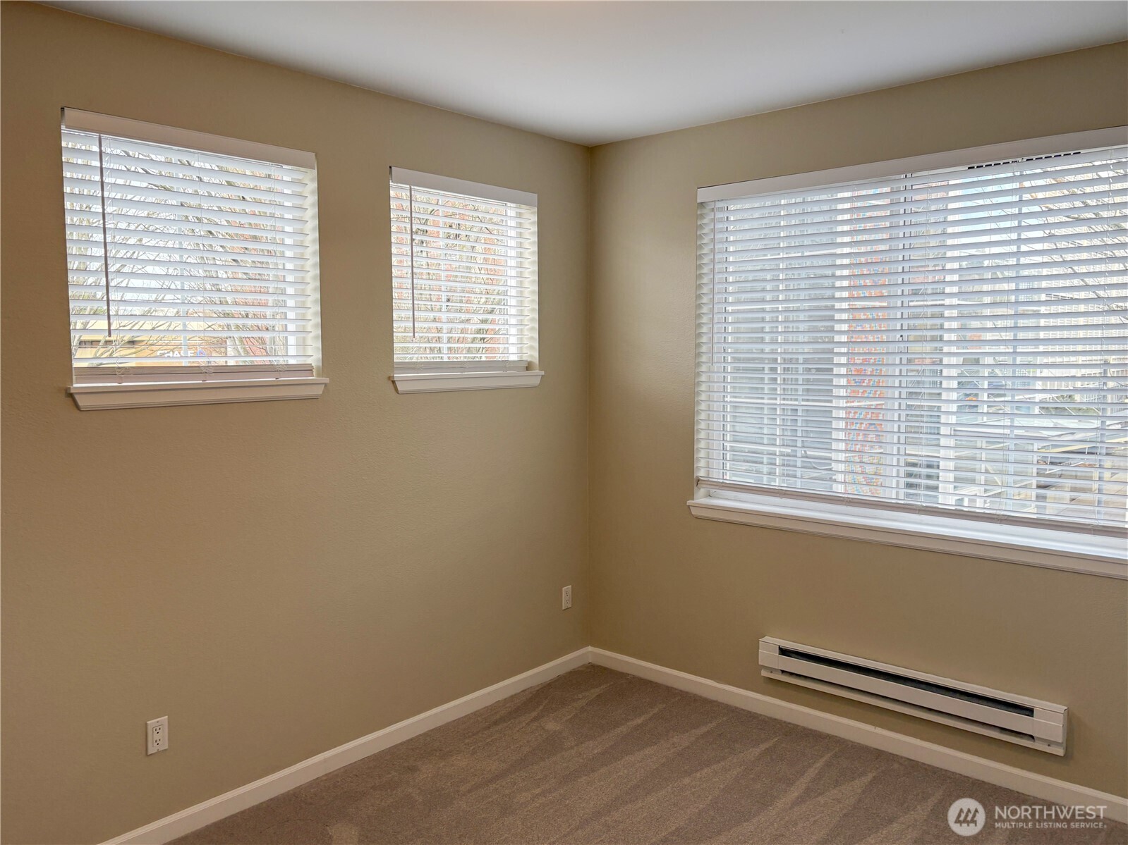Bright bedroom with large windows and a calm, neutral aesthetic ideal for rest or work-from-home needs.