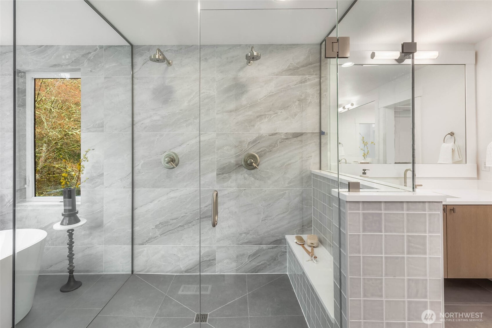 Gorgeous walk in shower with custom bench duel heads, designer selected tile, and frameless glass surround