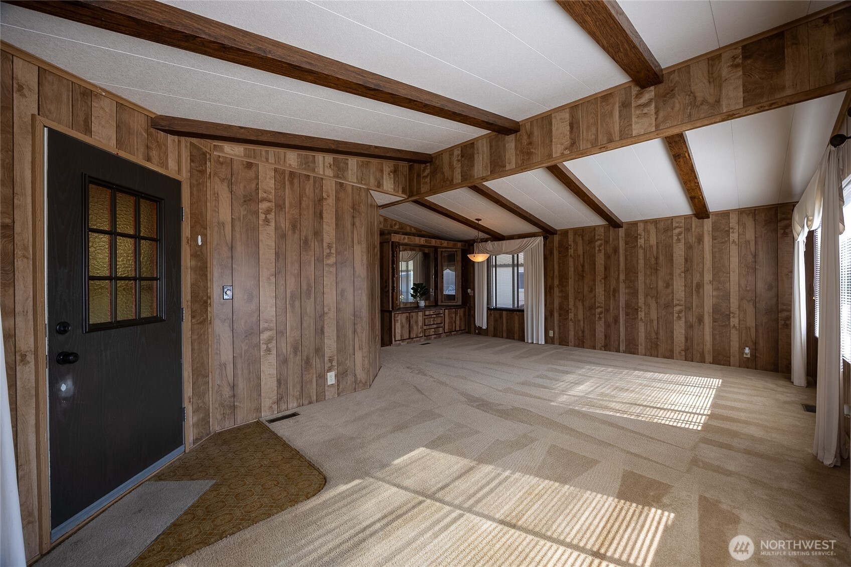 View of vaulted ceiling living room and dining room with built in cabinet.