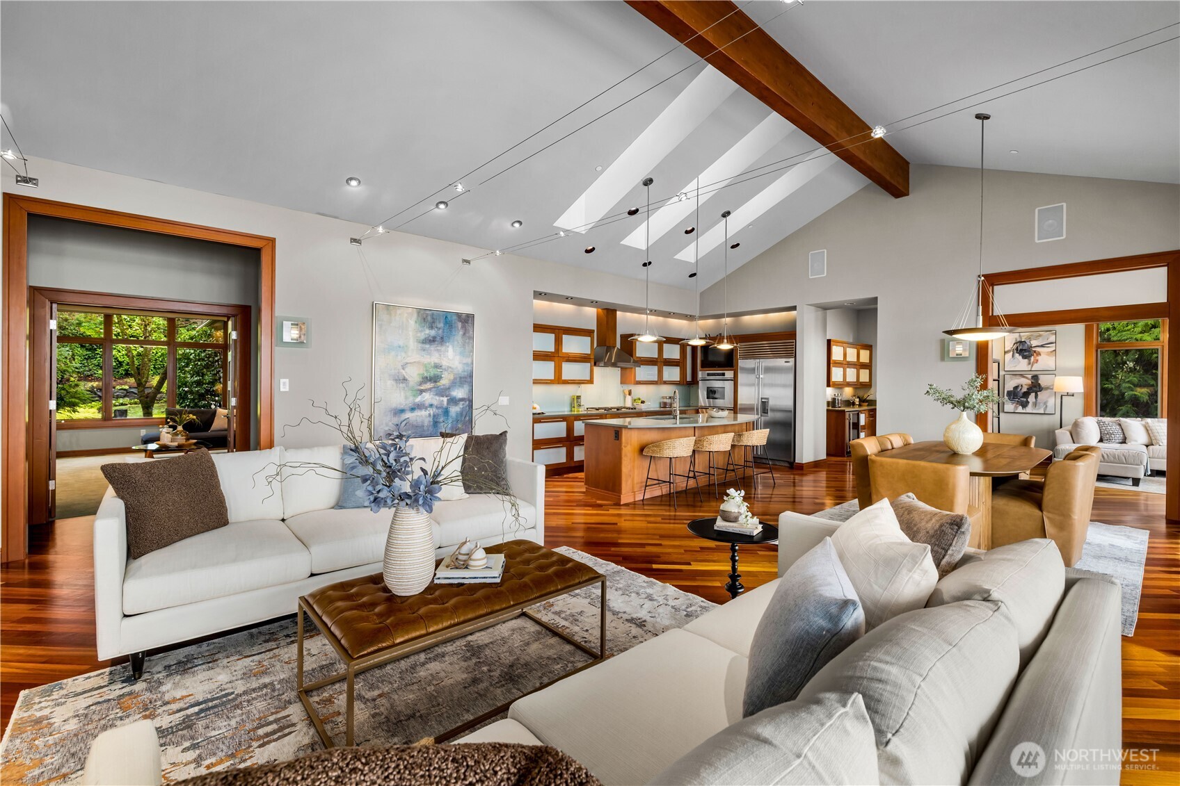 Expansive open-concept kitchen, dining, and living with vaulted ceilings, skylights, and rich hardwood floors.