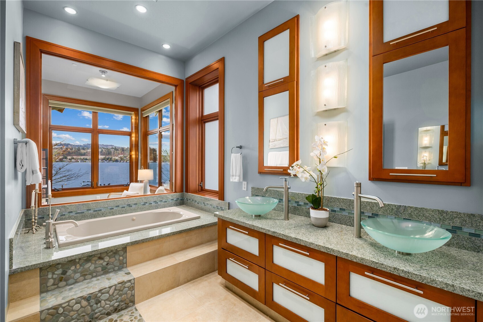 Well-appointed primary bath featuring dual vanities, vessel sinks, and custom cabinetry with stone surfaces.