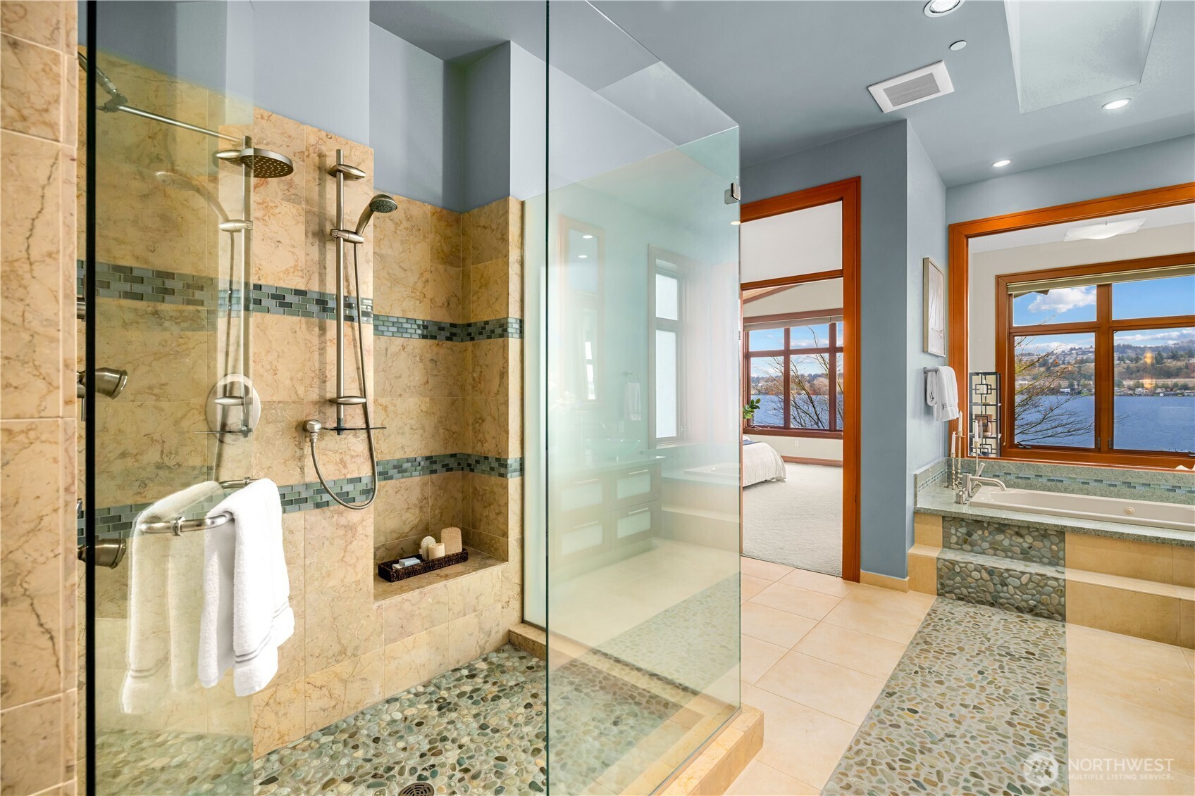 Clean lines and layered materials—dual glass vessel sinks, stone surfaces, and a soaking tub set beneath expansive windows.