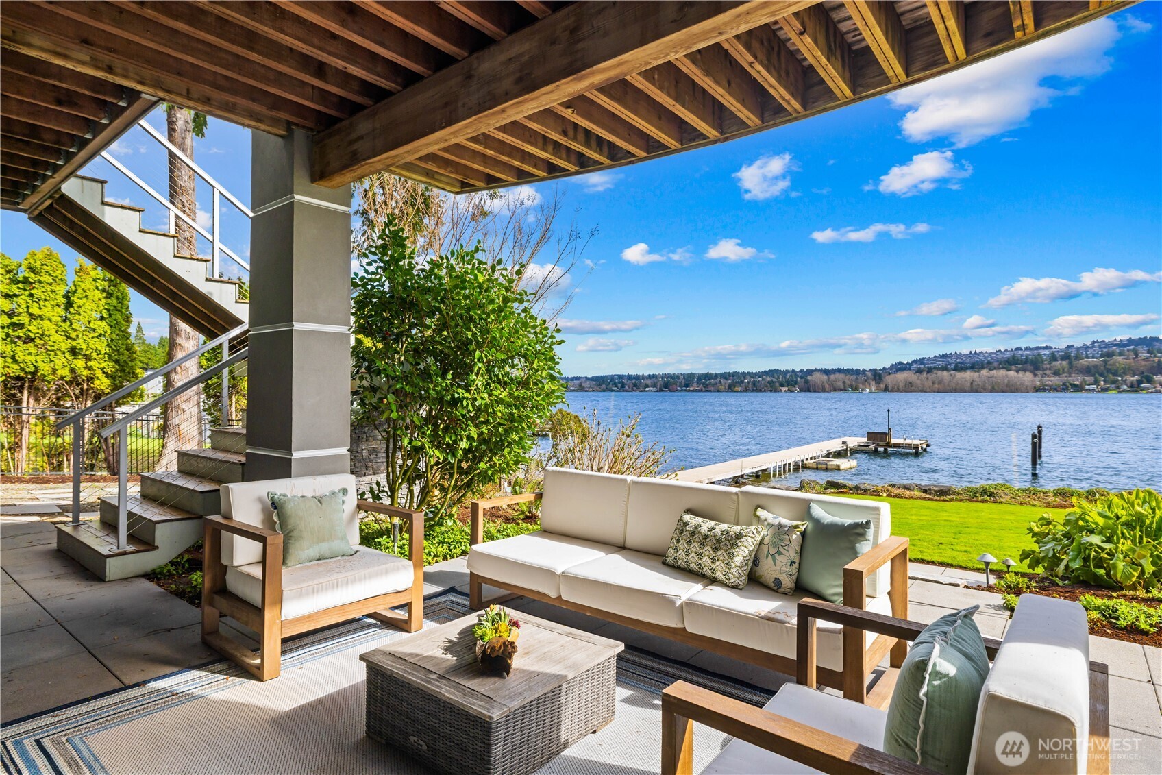 Expansive lower-level entertainment area featuring a stone fireplace, wet bar with quartz countertop, and full-height glass doors opening to the waterfront patio. Enjoy lake and mountain views from this versatile space, perfect for game nights and gatherings.