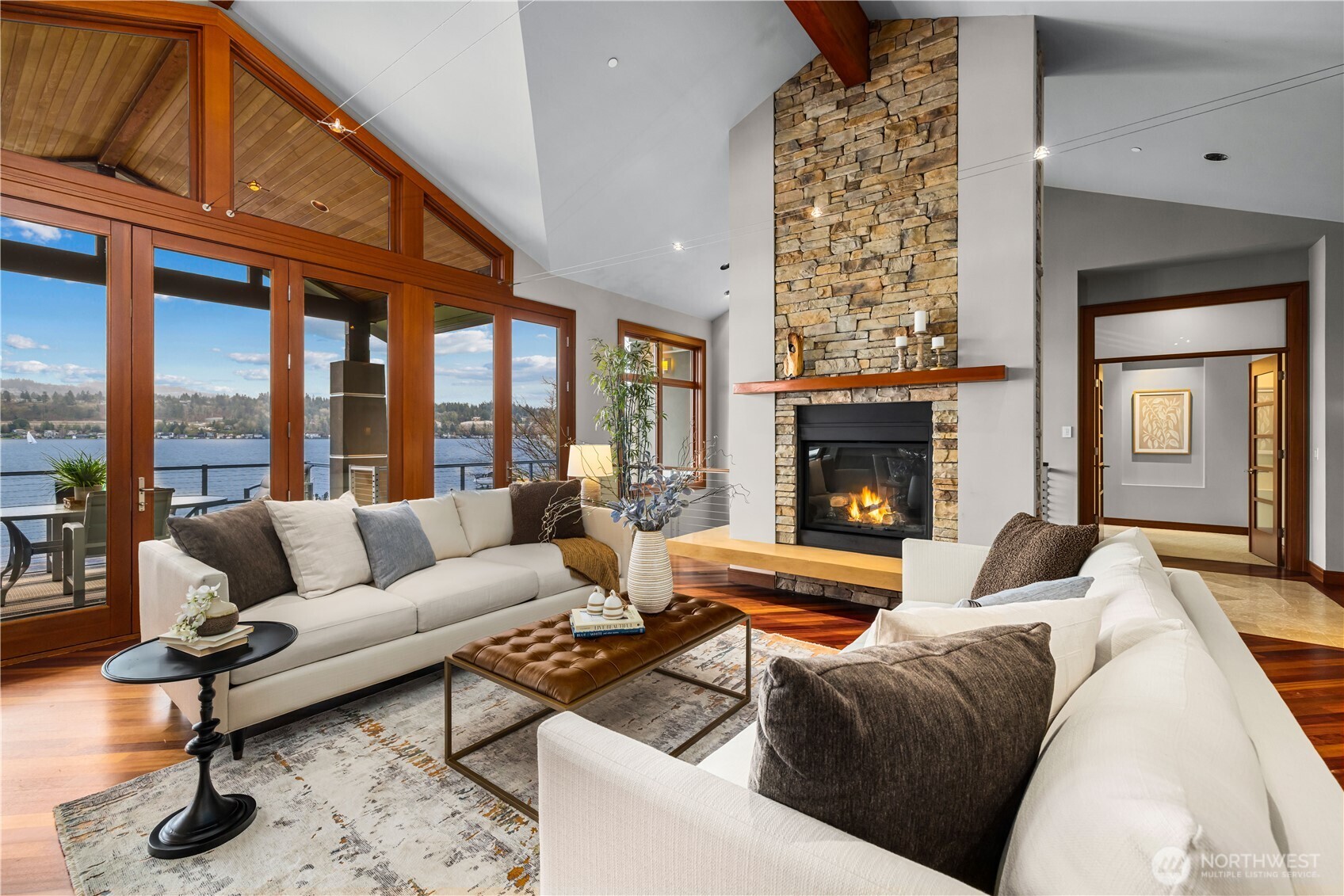 Where everyday living meets the water—walls of glass, a warm stone fireplace, and seamless connection to the lake beyond.