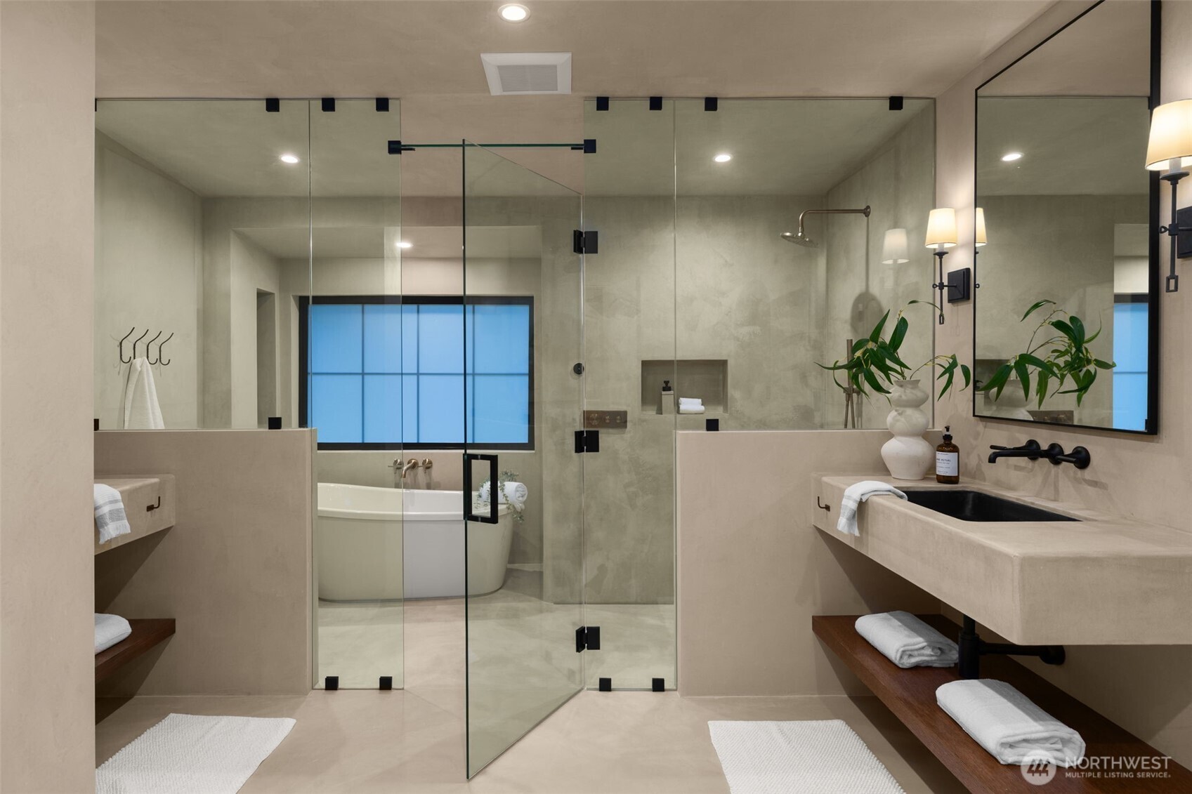 Elegant primary suite bath impresses with a glass shower enclosure with a freestanding tub and floating vanities