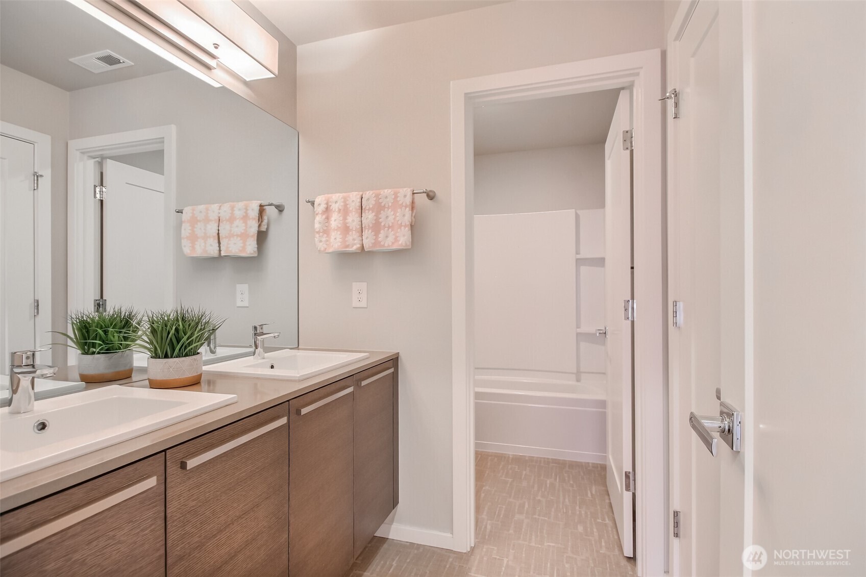 Hallway bath has double sinks and a private door for tub and toilet