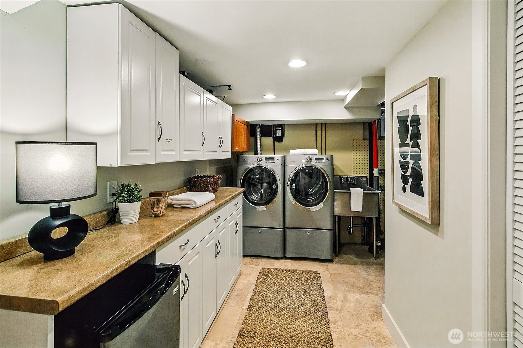The laundry room is clean, modern, and multifunctional and has lots of storage space.