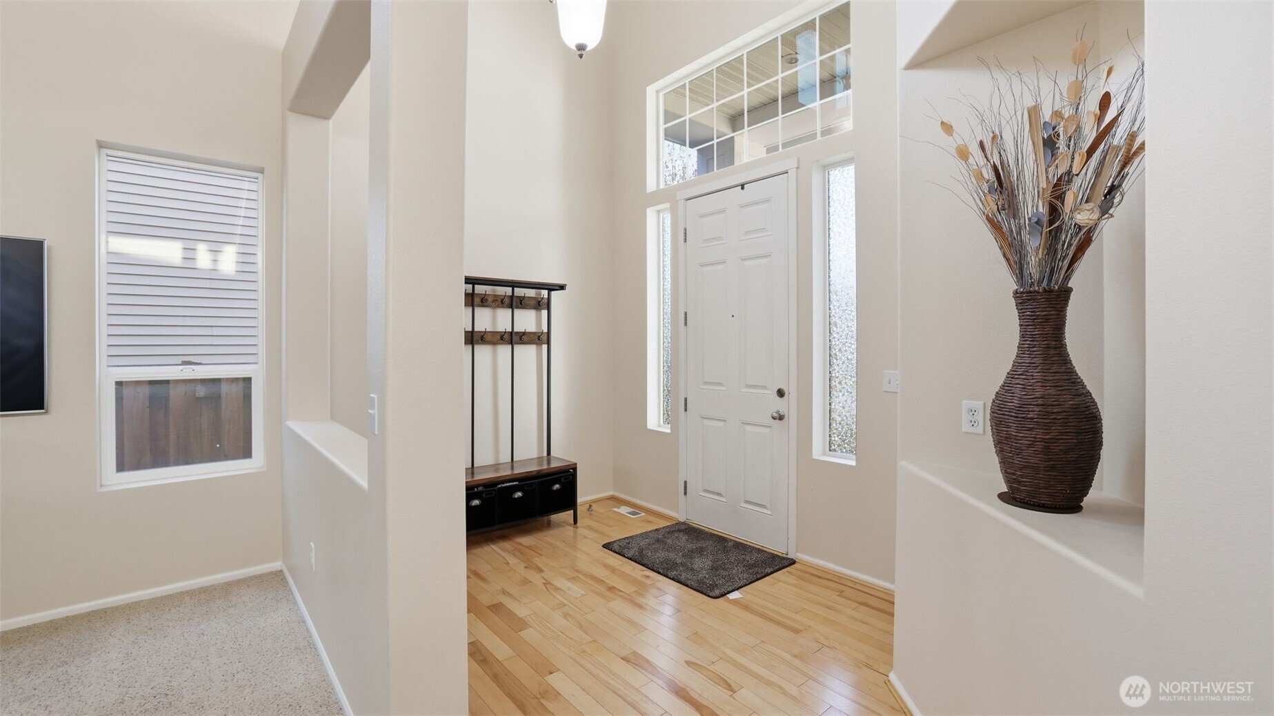 A bright and welcoming entry greets you with high ceilings, abundant natural light, and timeless hardwood flooring.