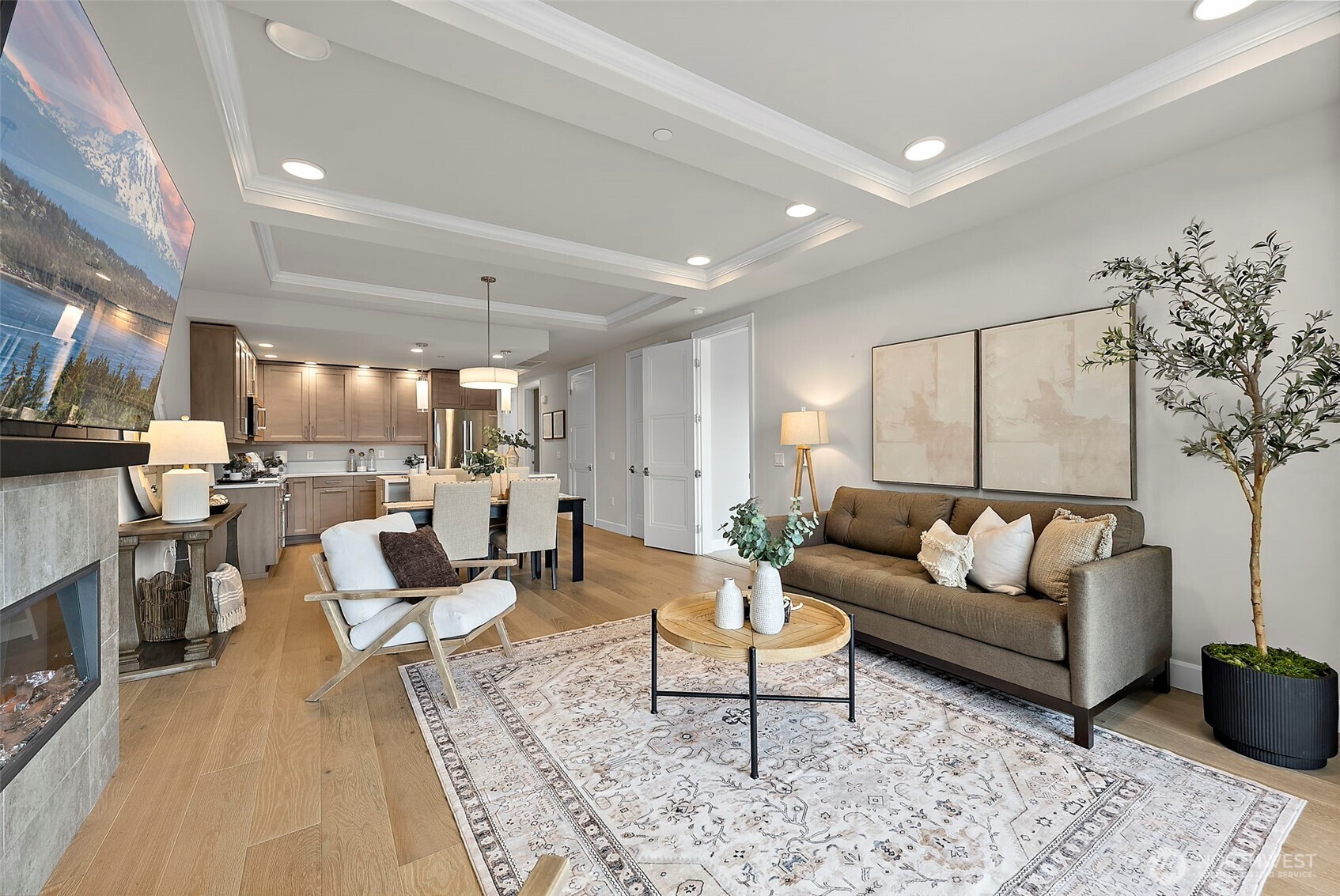Elevated modern living room featuring a fireplace for cozy winter days and spring mornings, vinyl plank flooring, recessed lighting. Open concept layout promotes seamless flow from living to dining to kitchen areas.