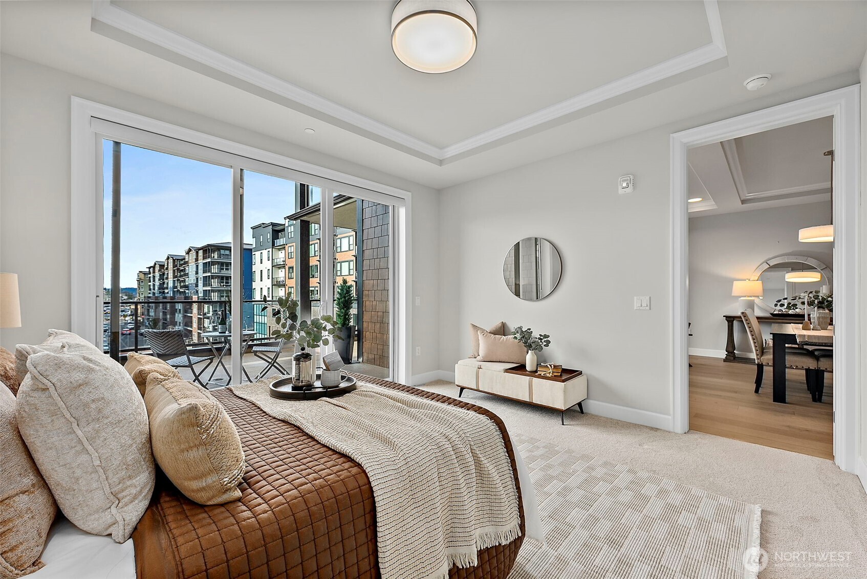 Primary bedroom suite of the living room with carpeted floors, glass slider that leads out to private balcony/deck with a Village View of Point Ruston community.