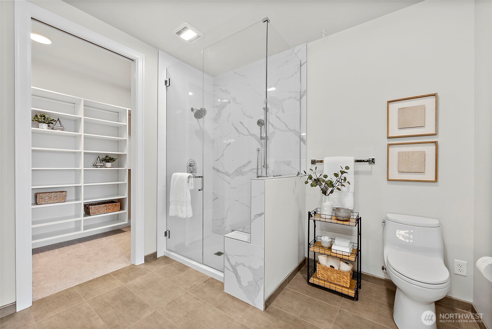 Primary en-suite bathroom with walk-in shower that features glass surround, sitting bench and dual mounted shower heads. Walk through to the walk-in closet.