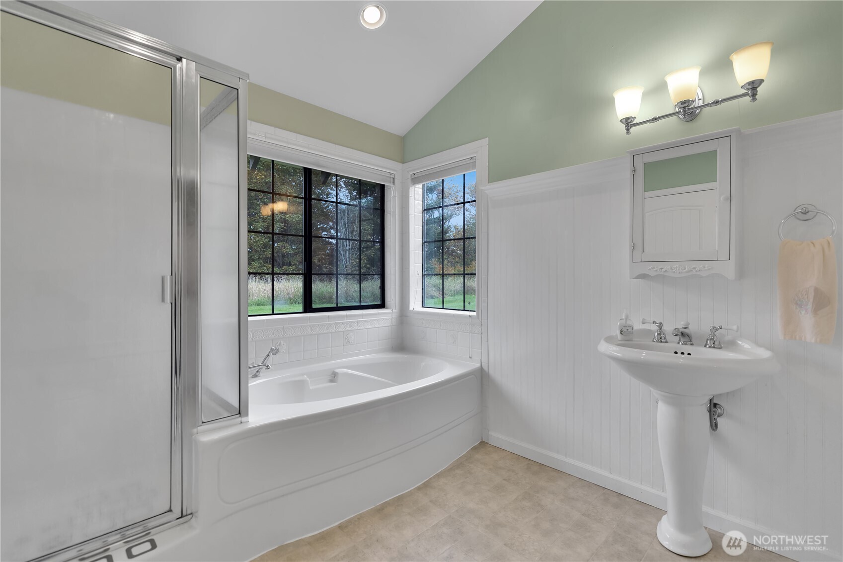 Primary bath with a vaulted ceiling, soaking tub, and separate shower.