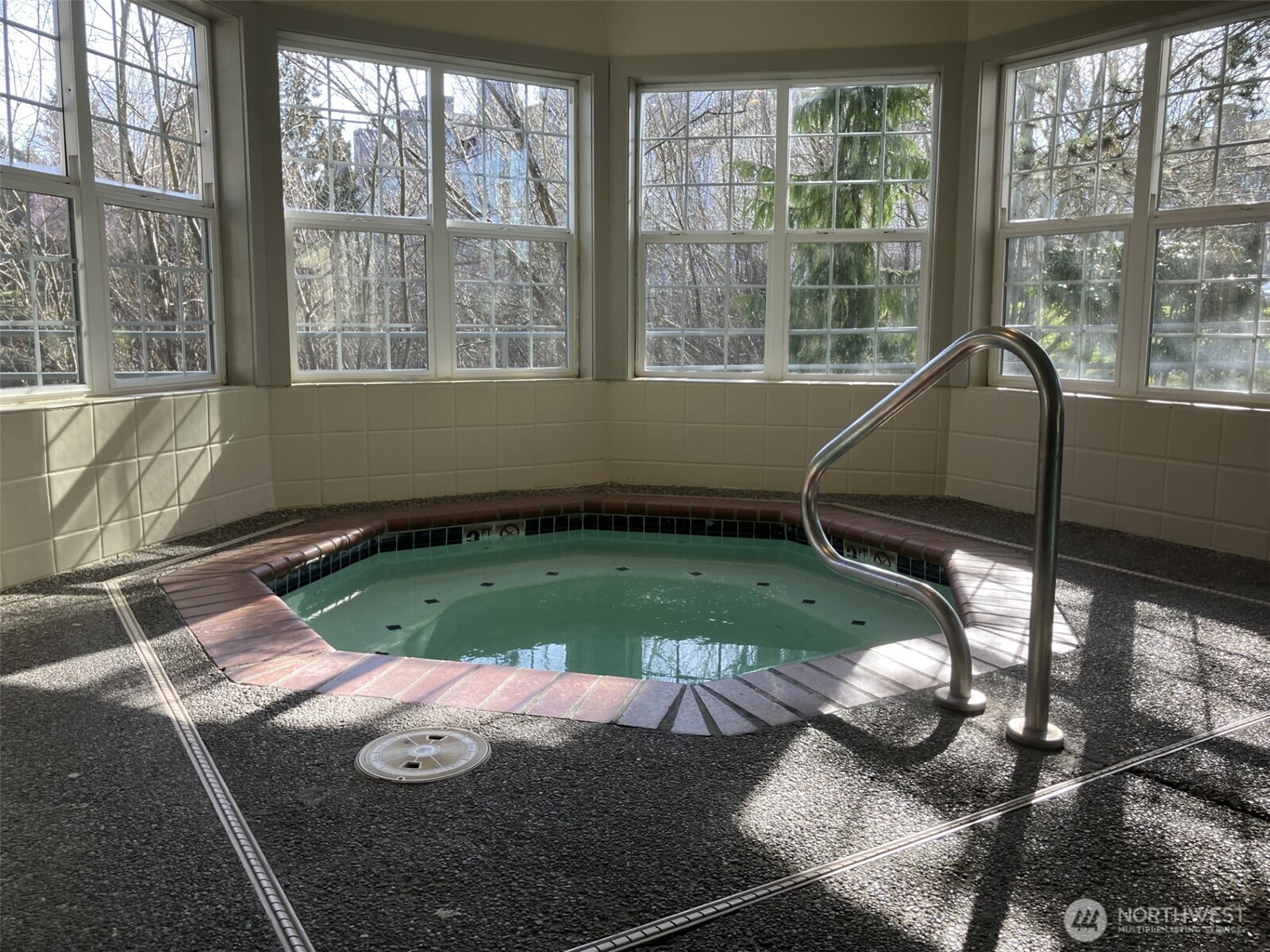 Large hot tub bathed by plenty of light through the many windows.