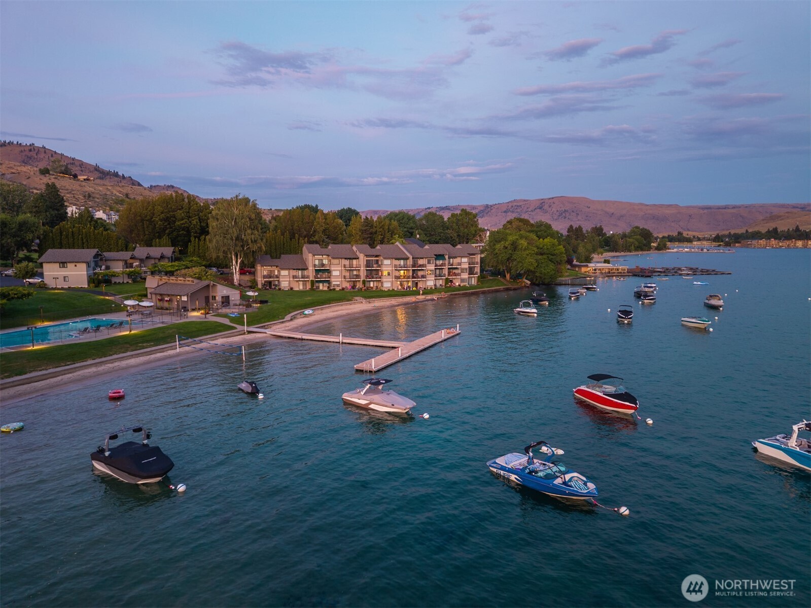 Aerial view of Spader Bay property with Olympic-sized pool, grassy lawn, sandy beach, waterfront, T-dock and mooring buoys.