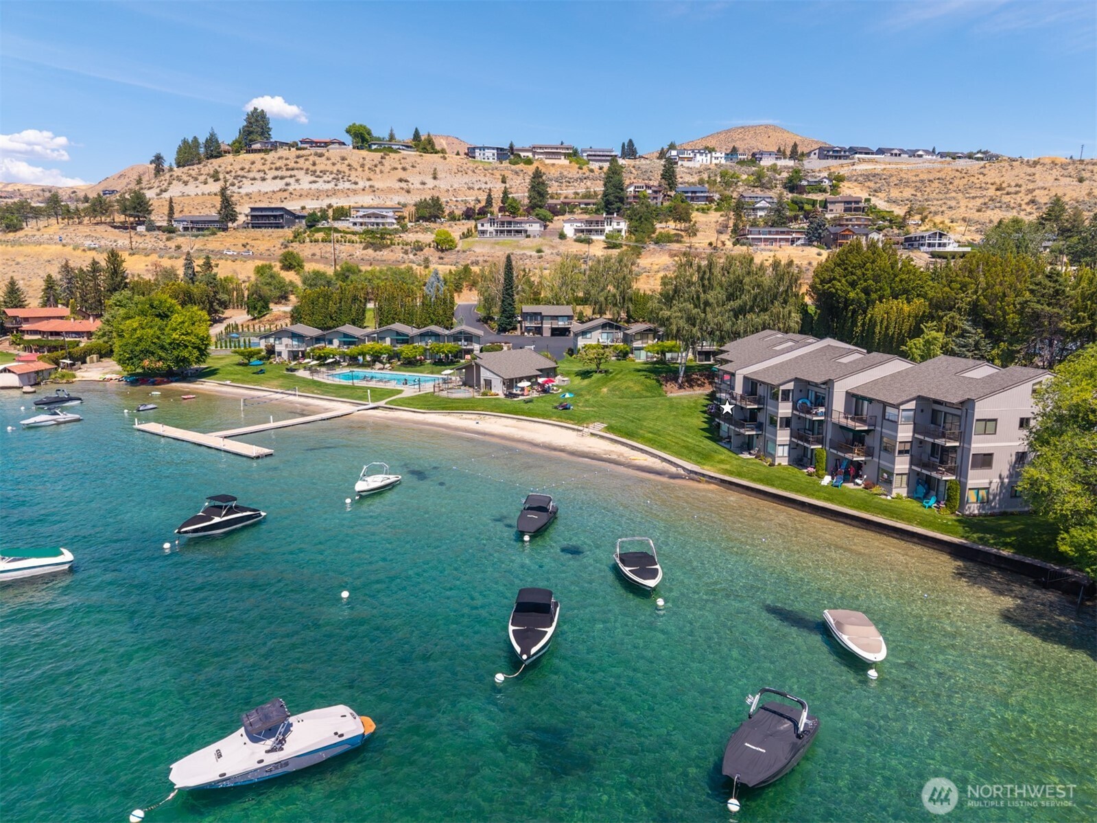 Aerial view of Spader Bay property with grassy lawn, sandy beach, waterfront, T-dock and mooring buoys.