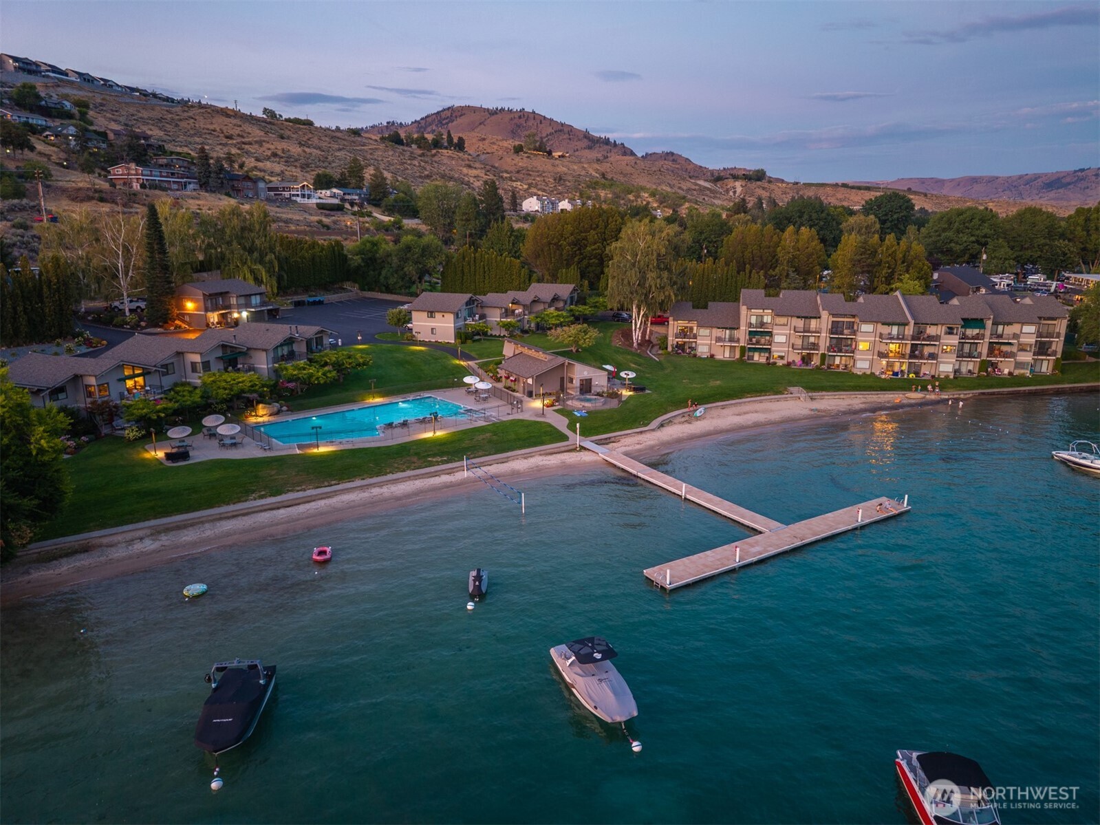 Aerial view of Spader Bay property with Olympic-sized pool, grassy lawn, sandy beach, waterfront, T-dock and mooring buoys.