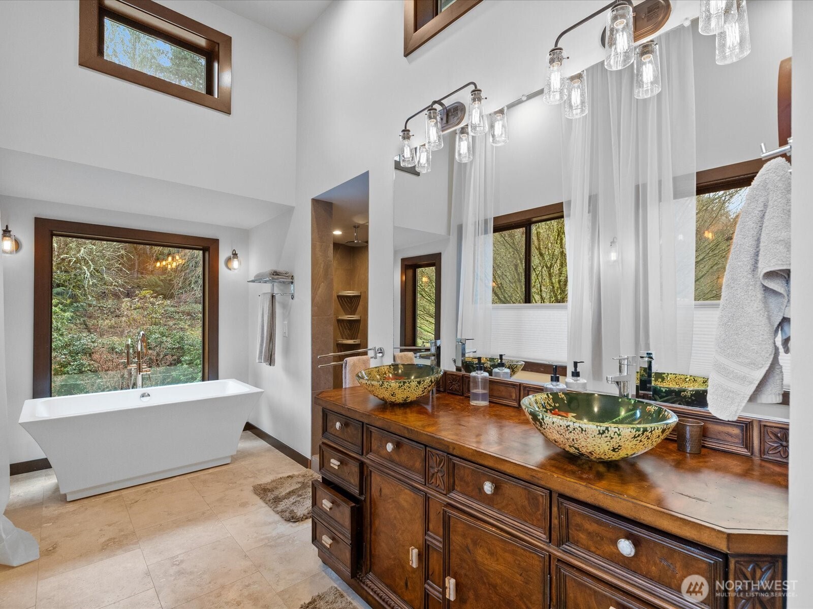 Custom double vanity with vessel sinks and warm wood cabinetry. Plentiful large windows to bring in lots of natural light.