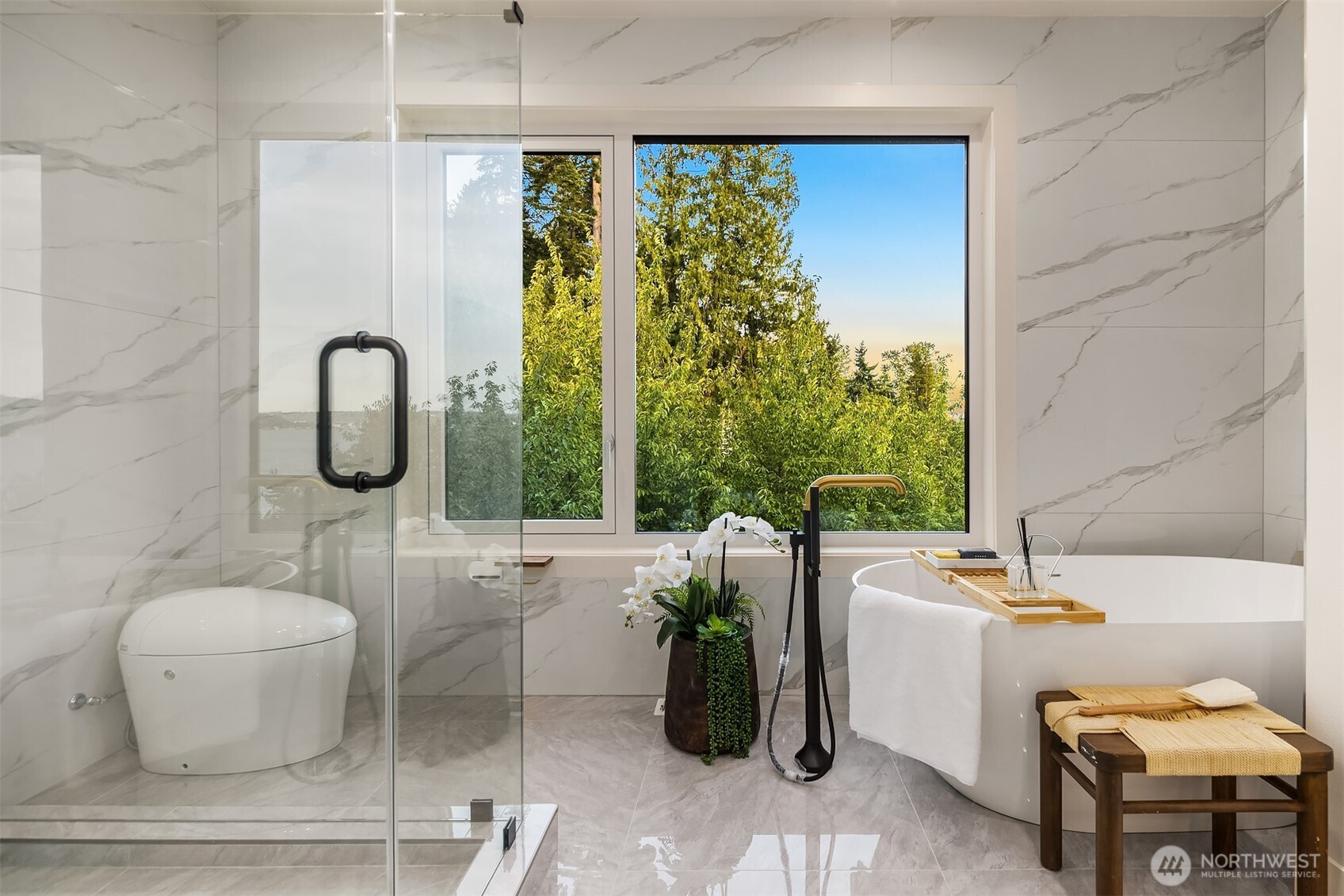 Serene spa retreat with a freestanding soaking tub, glass-enclosed shower, and lush treetop views