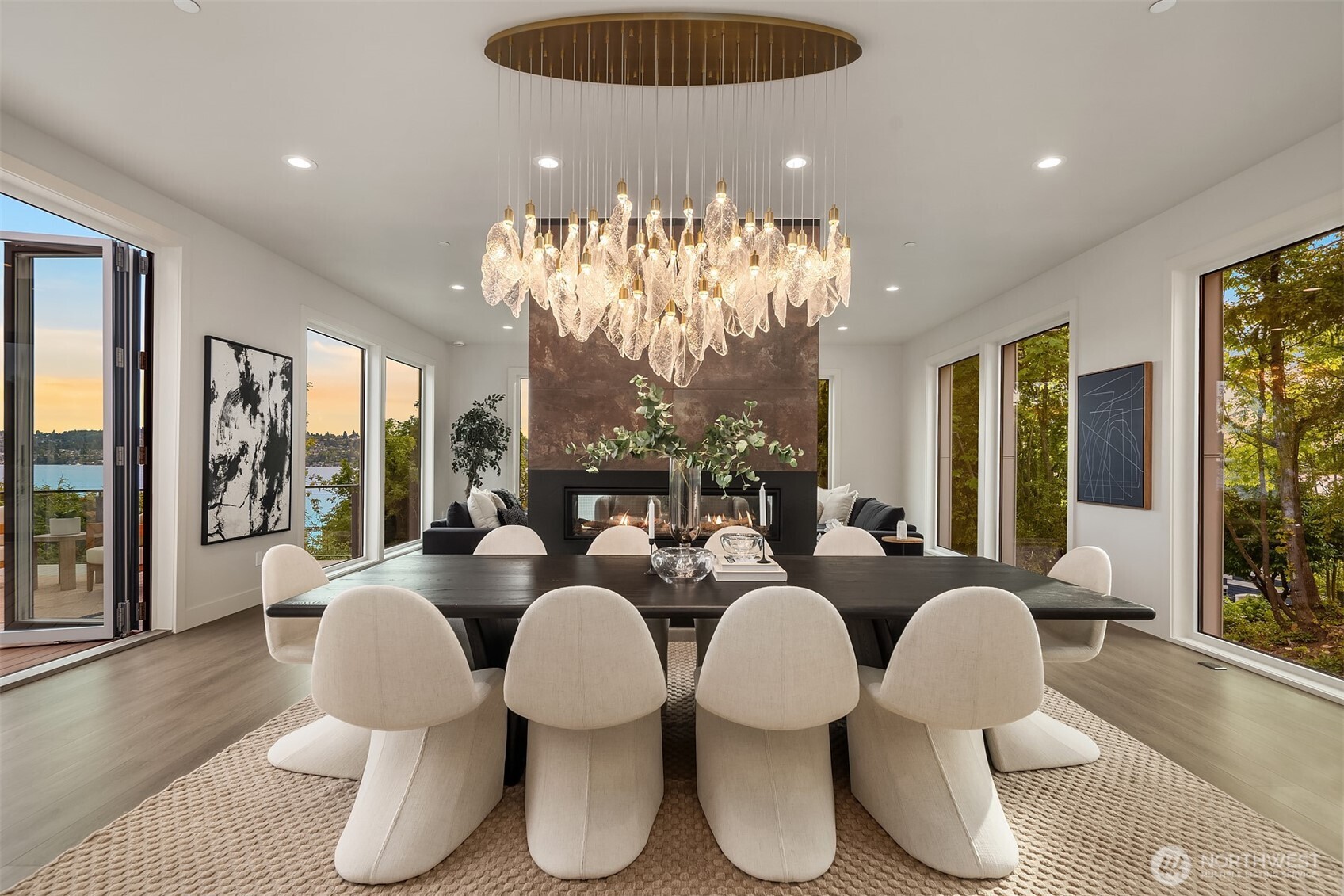 Wall-to-wall windows, operable glass walls, a sculptural chandelier, and a double-sided fireplace set the stage for dining with style and a view.