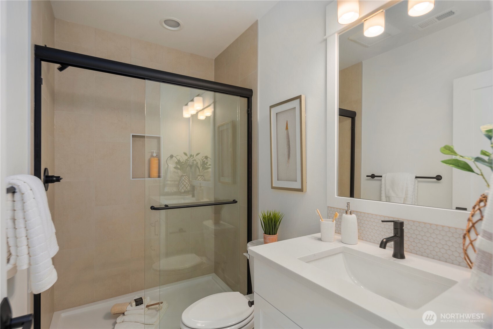 Main Level Bath: Full bathroom with modern fixtures, tiled shower, and quartz-topped vanity, providing convenience for guests or a main-level bedroom.  Staged photos are of the model home of the same floorplan within the Foxmoore community and are for visualization purposes only. Colors, finishes, and layout can and will vary.
