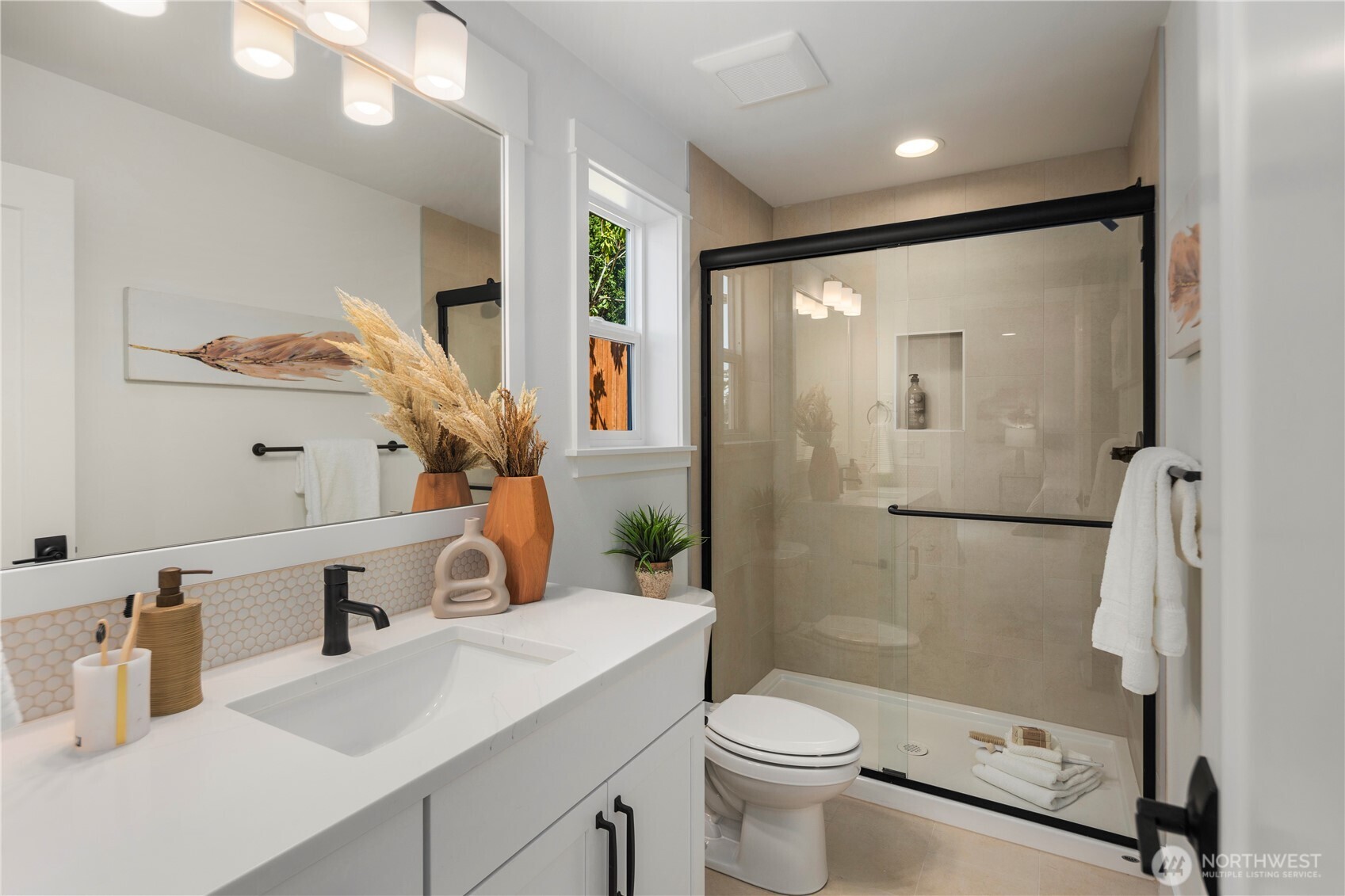Lower Level Ensuite Bath: Thoughtfully designed en-suite bath offers a quartz-topped vanity, framed mirror, and a walk-in shower with full-height tile surround. Conveniently located off the lower-level suite, it ensures both style and privacy for guests.  Staged photos are of the model home of the same floorplan within the Foxmoore community and are for visualization purposes only. Colors, finishes, and layout can and will vary.