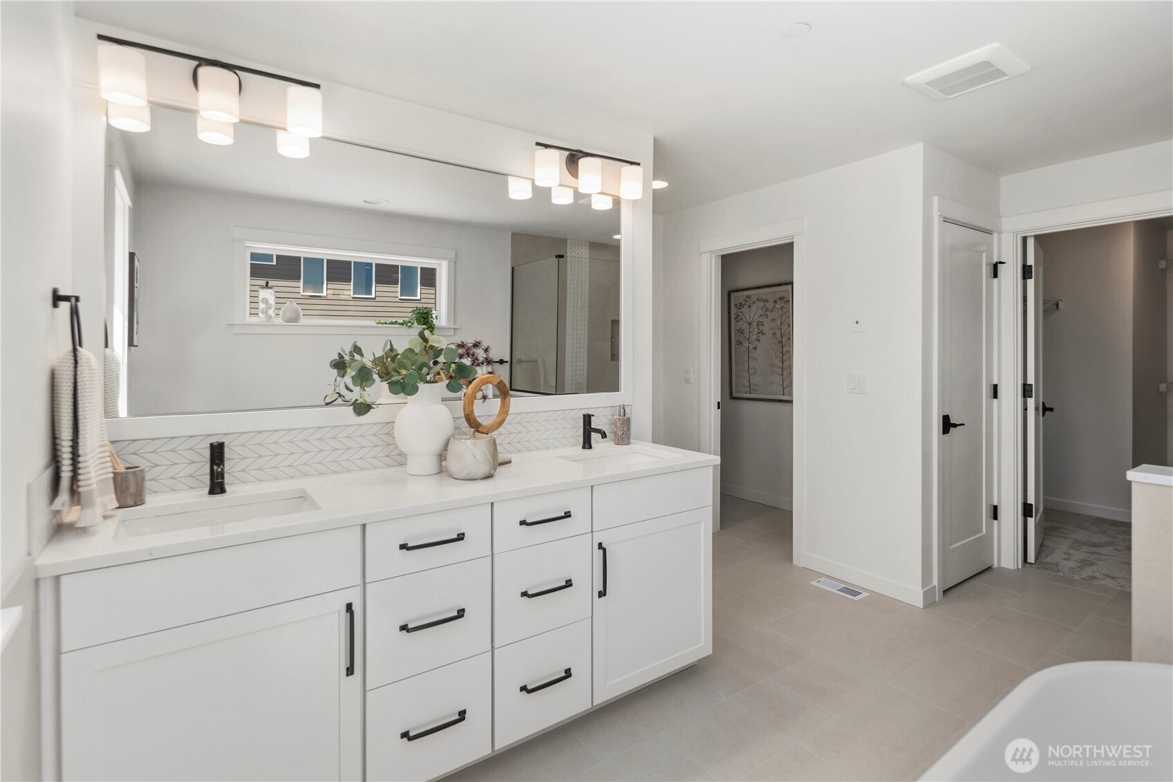 Primary Bathroom – Vanity: The spa-inspired primary bathroom features a double-sink vanity with sleek finishes, modern fixtures, and ample storage for everyday convenience. A wide mirror and abundant lighting elevate both style and functionality.  Staged photos are of the model home of the same floorplan within the Foxmoore community and are for visualization purposes only. Colors, finishes, and layout can and will vary.