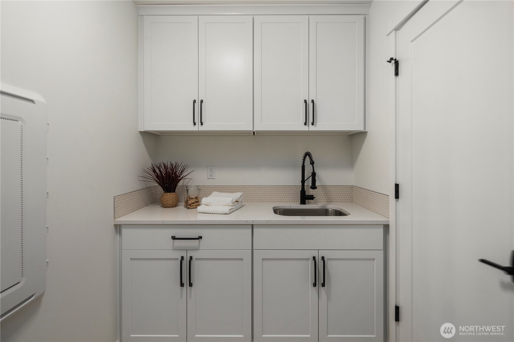 Laundry Room: Bright and functional laundry space with upper and lower cabinetry, quartz counters, and a deep sink for easy cleanup. The washer and dryer hookup is ready for your appliances, and extra storage keeps everything organized.  Staged photos are of the model home of the same floorplan within the Foxmoore community and are for visualization purposes only. Colors, finishes, and layout can and will vary.