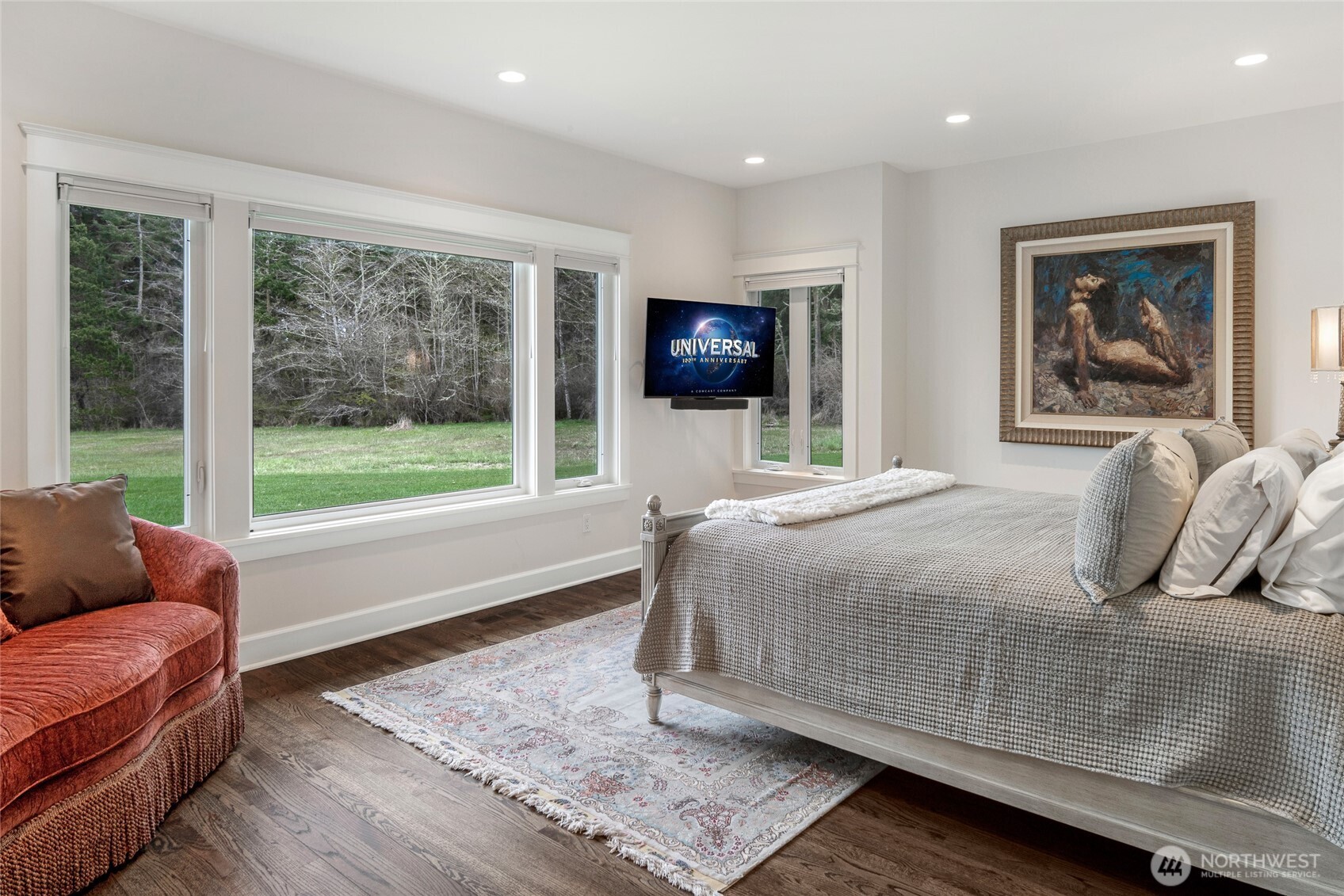 Light-filled bedroom with large picture windows overlooking manicured lawns and private acreage, offering serene views and natural light throughout.