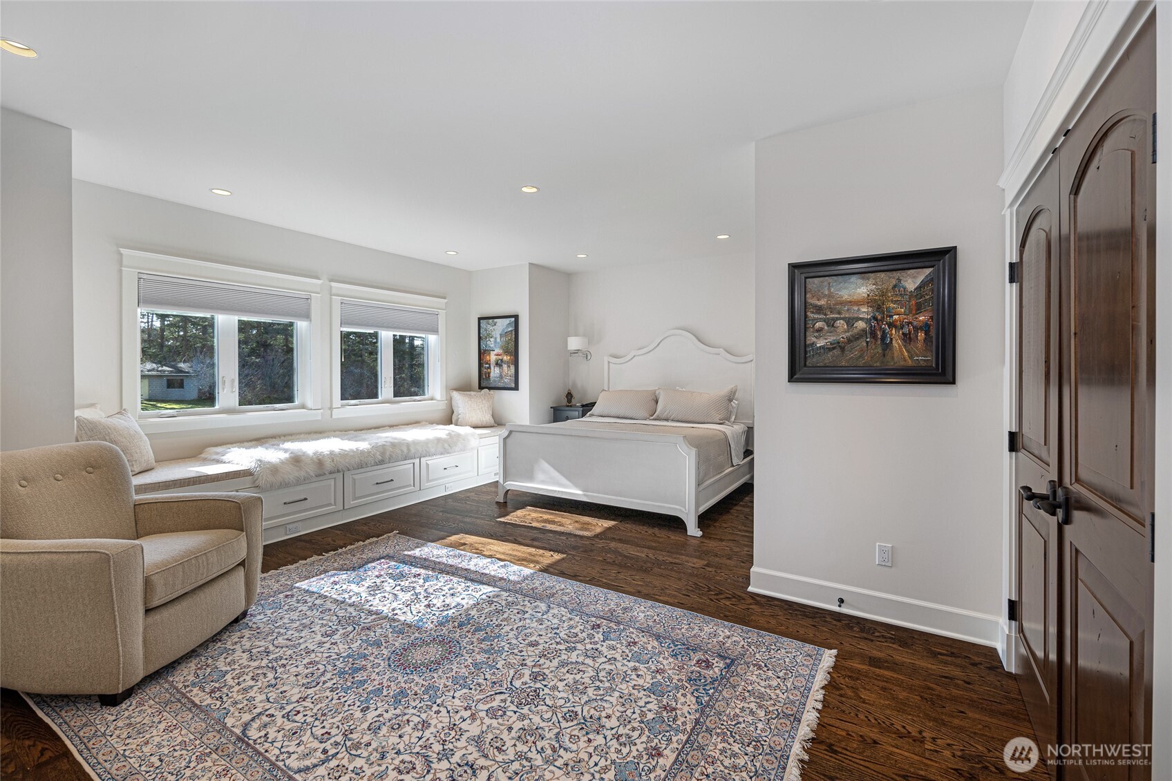Bright secondary bedroom with custom millwork, window seating, and peaceful views across landscaped grounds.