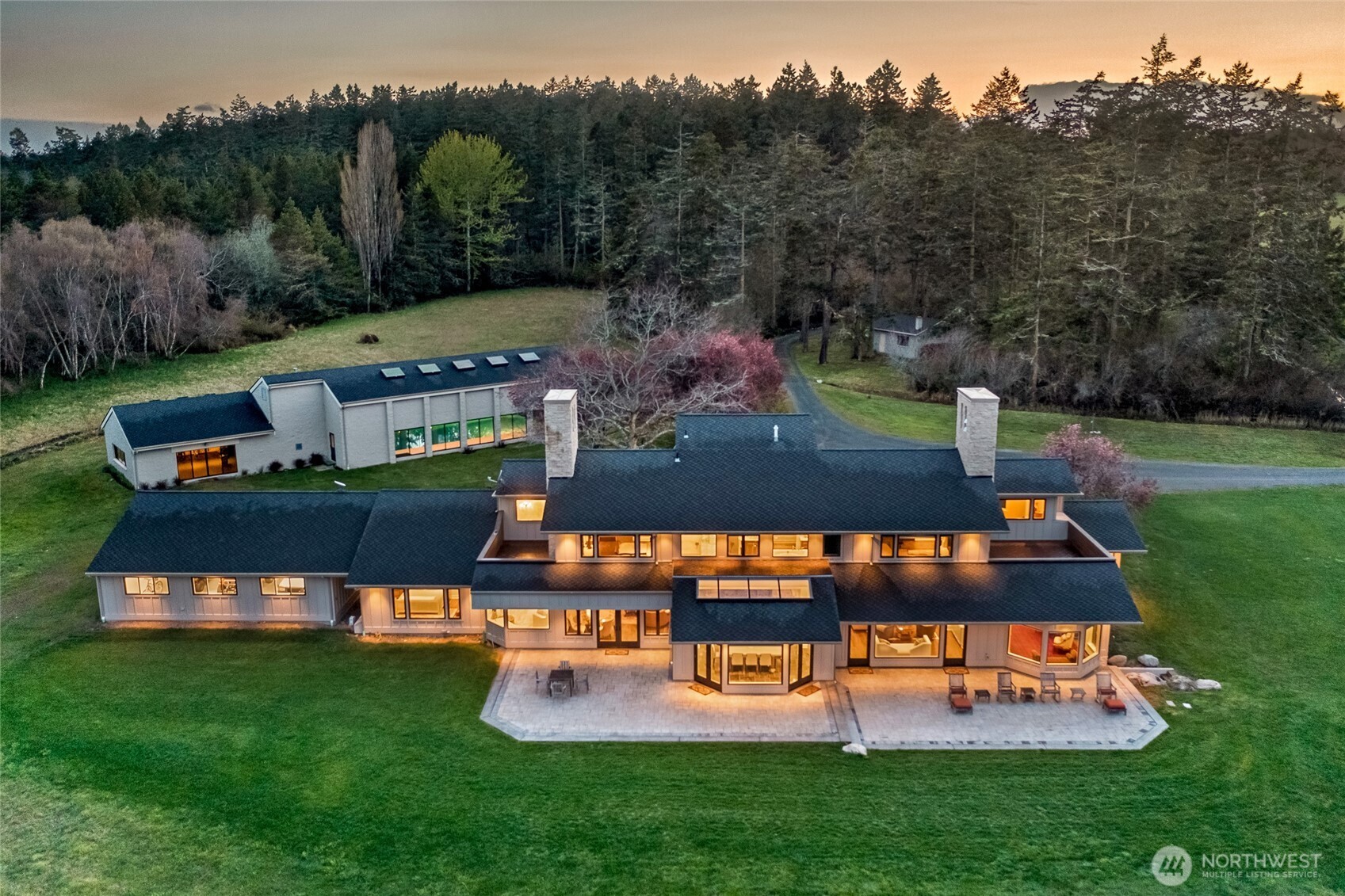Evening aerial capturing the residence, terraces, and pond framed by mature evergreens, offering exceptional privacy across 63± acres of waterfront property.