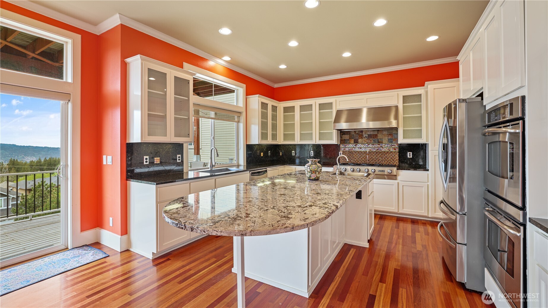 A chef's dream: spacious gourmet kitchen with an expansive island, granite countertops, top-tier GE Elite appliances, 5-burner Jenn-Air gas stove and double ovens.
